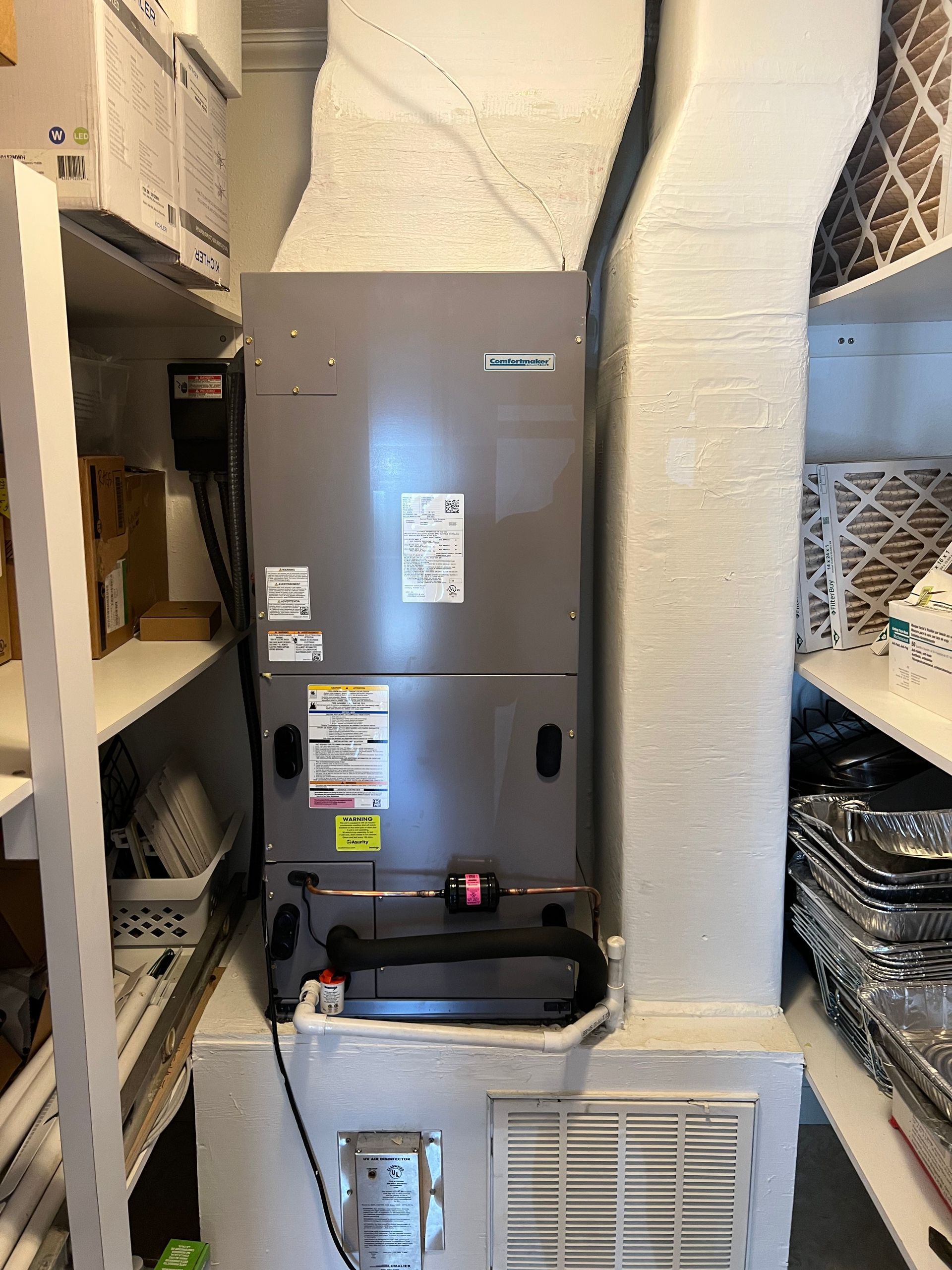 a gray air conditioner is sitting in a corner of a room .