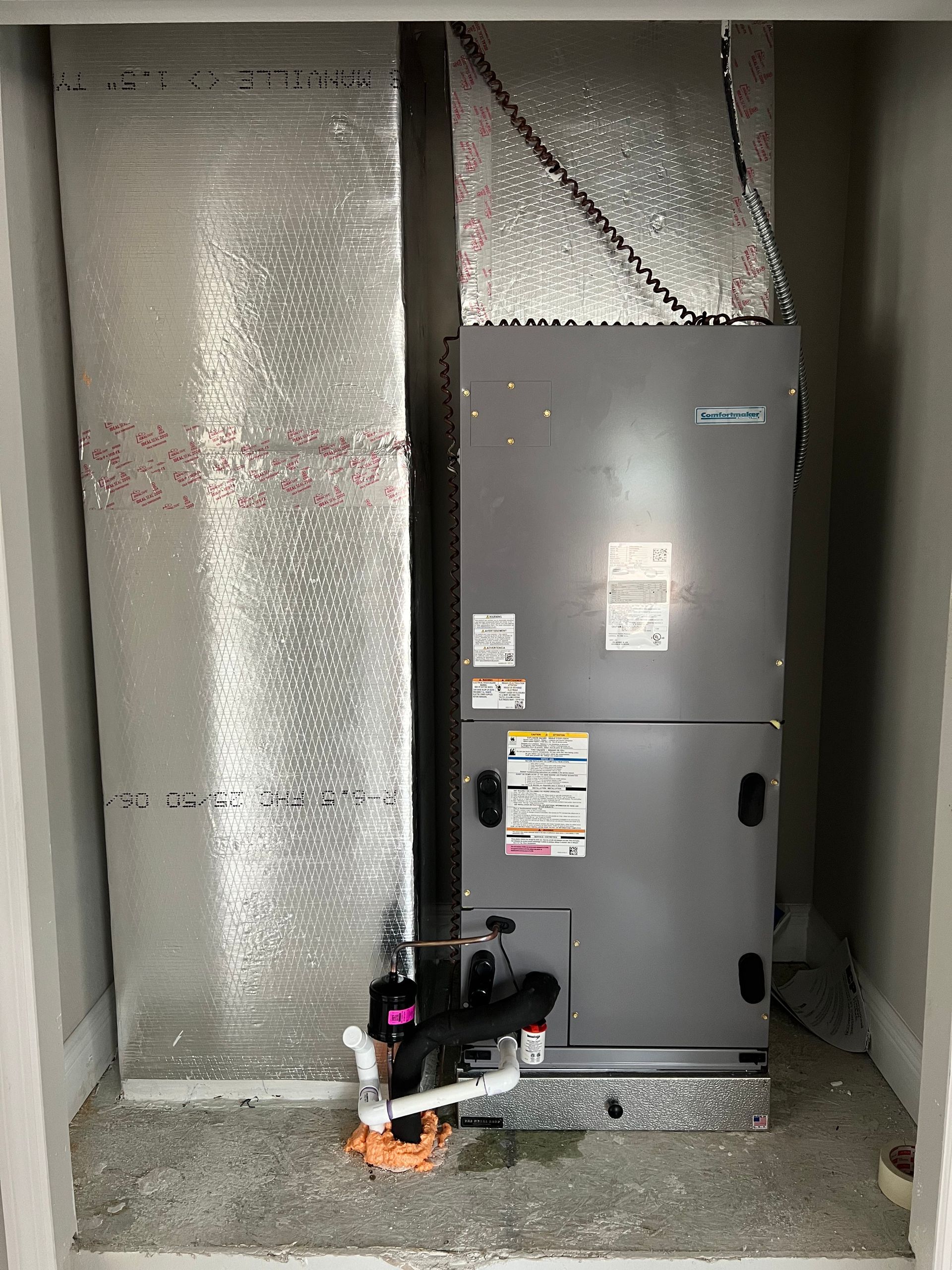 a gray air conditioner is sitting in a room next to a wall .