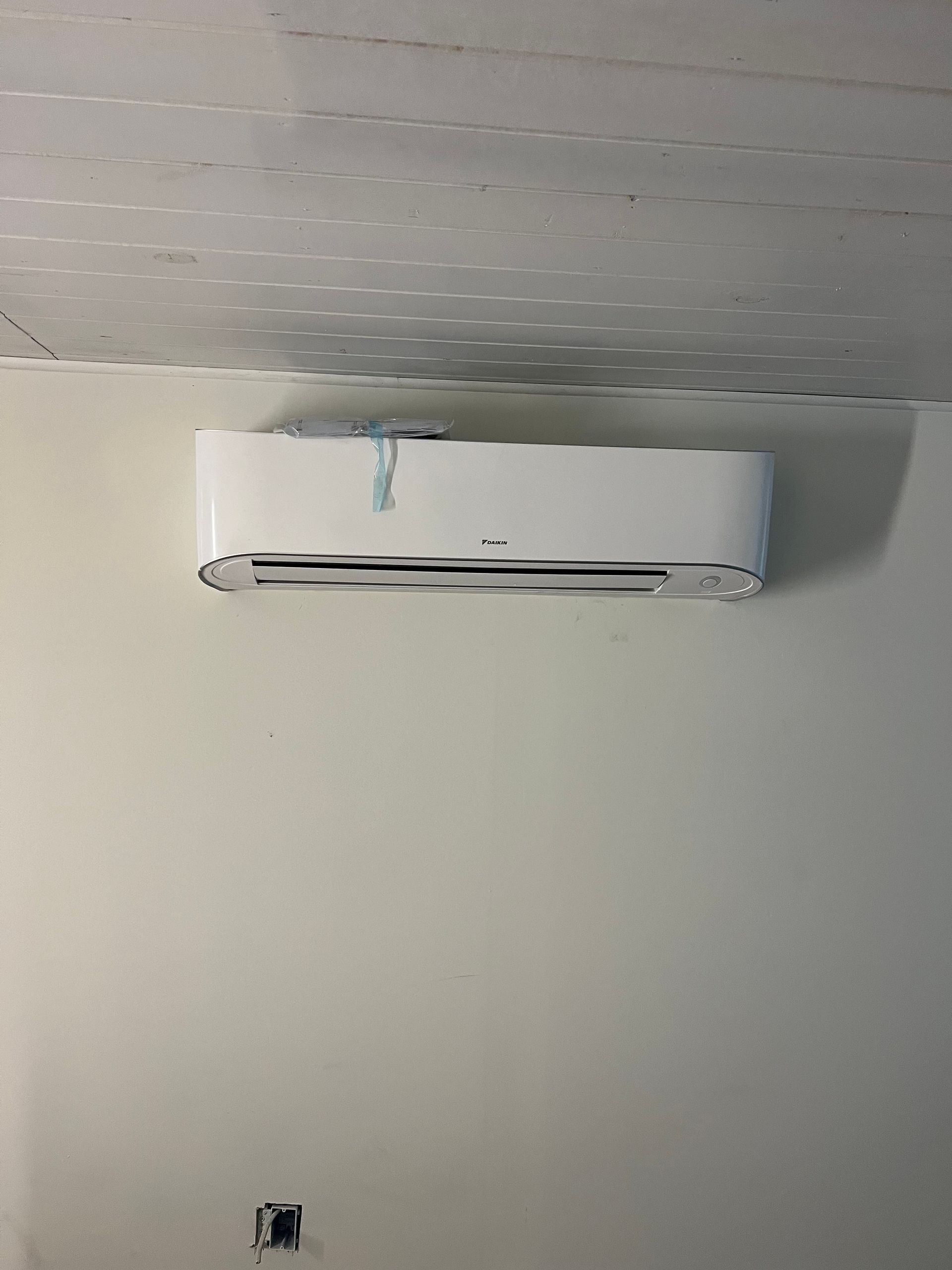 a white air conditioner is hanging from the ceiling in a room .