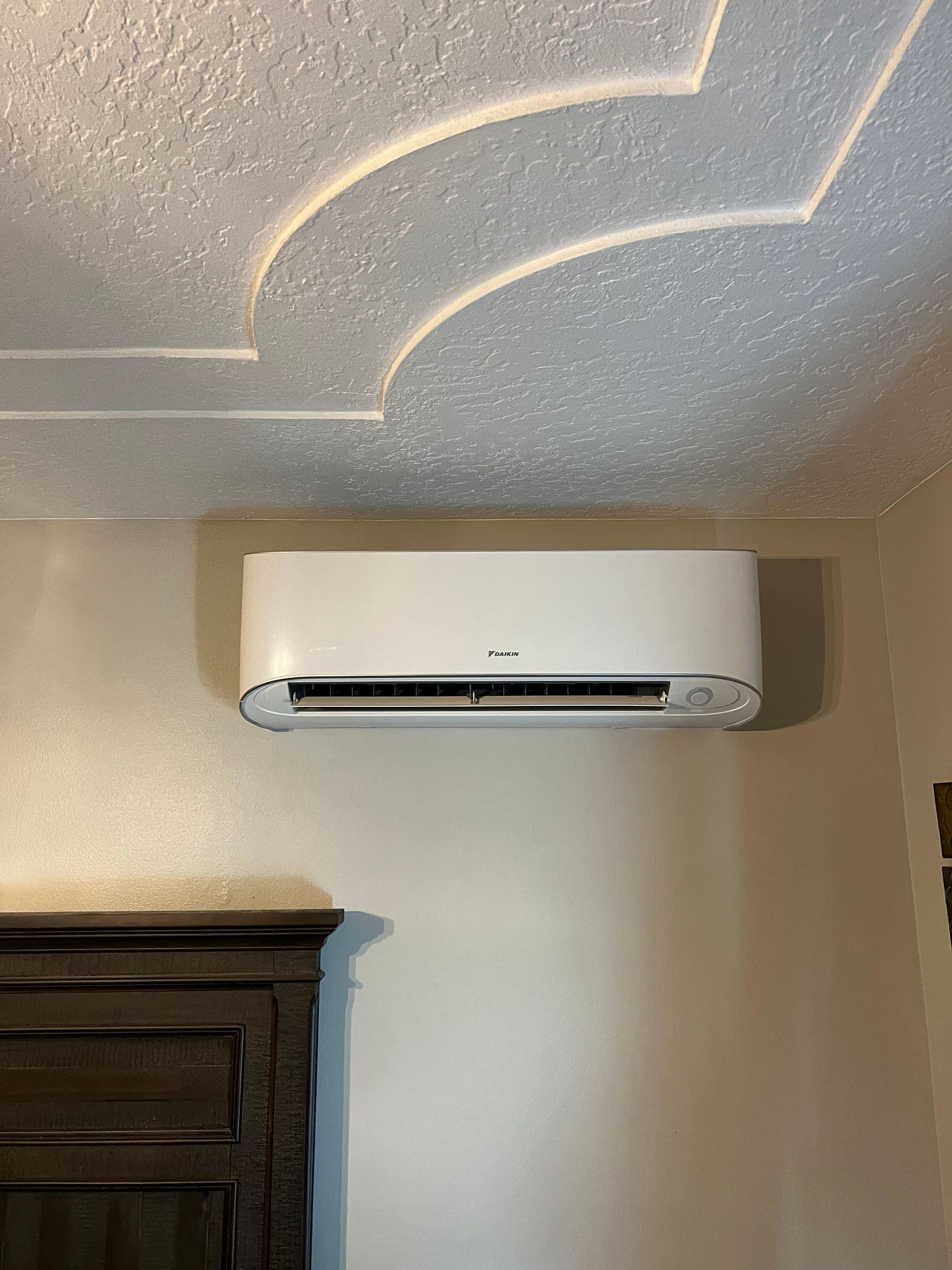 a white air conditioner is hanging on a wall in a room .