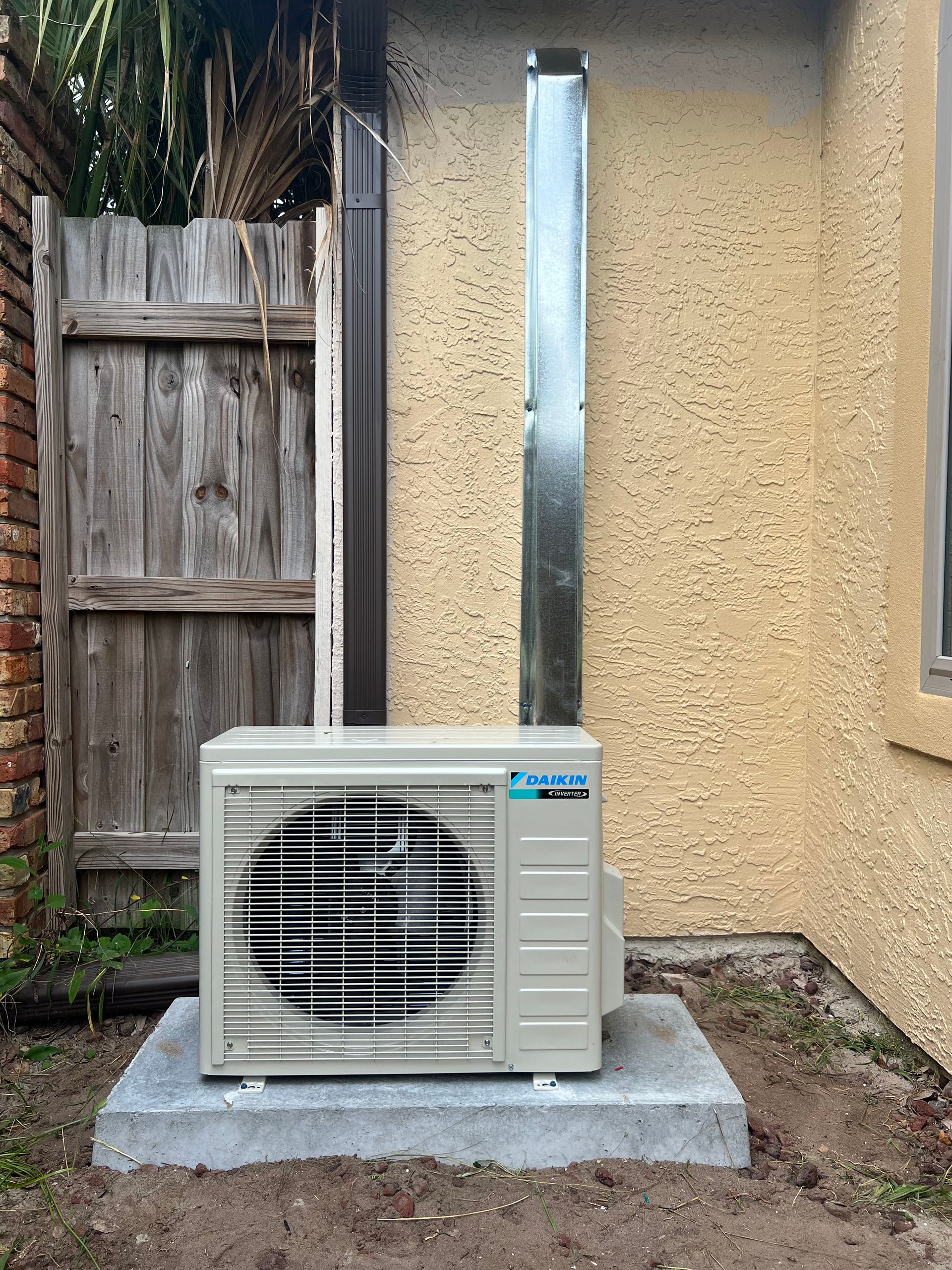 a large air conditioner is sitting outside of a house next to a wooden fence .