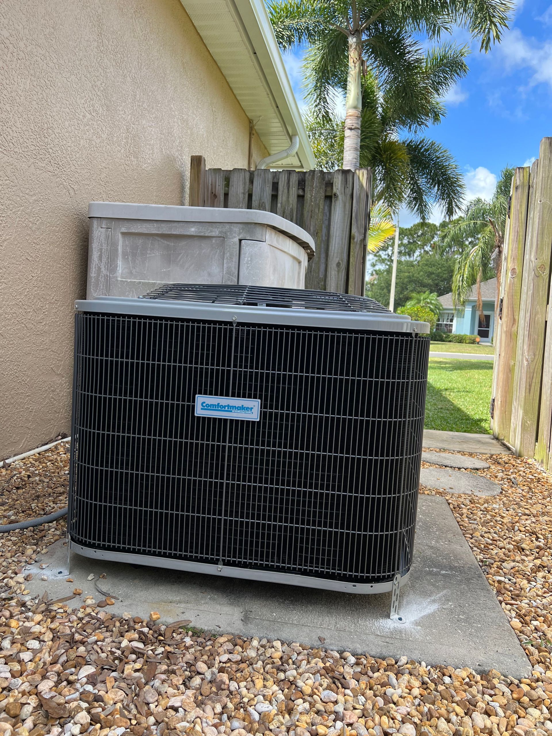 a black air conditioner is sitting outside of a house .