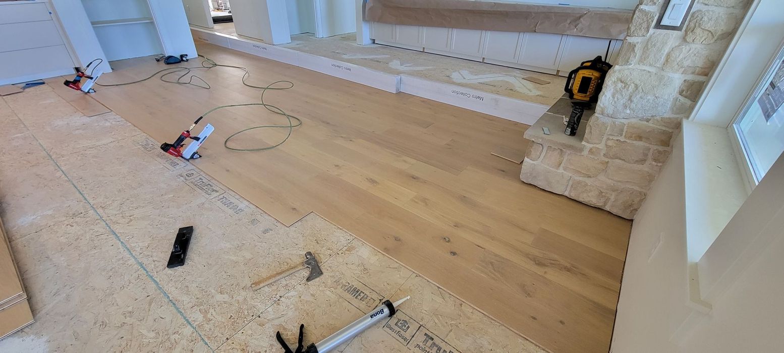 A wooden floor is being installed in a room with stairs.