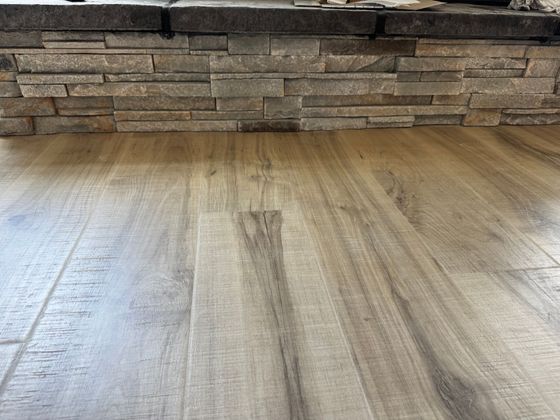 A wooden floor in a living room next to a fireplace.