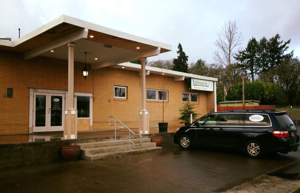 A black van is parked in front of a building.