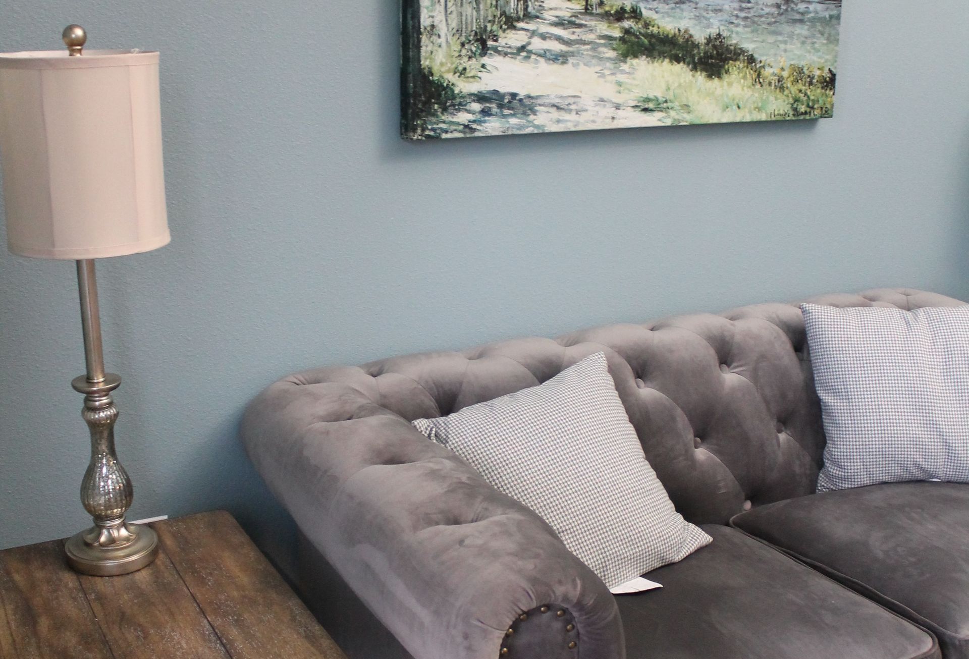 A living room with a couch , lamp , and painting on the wall.