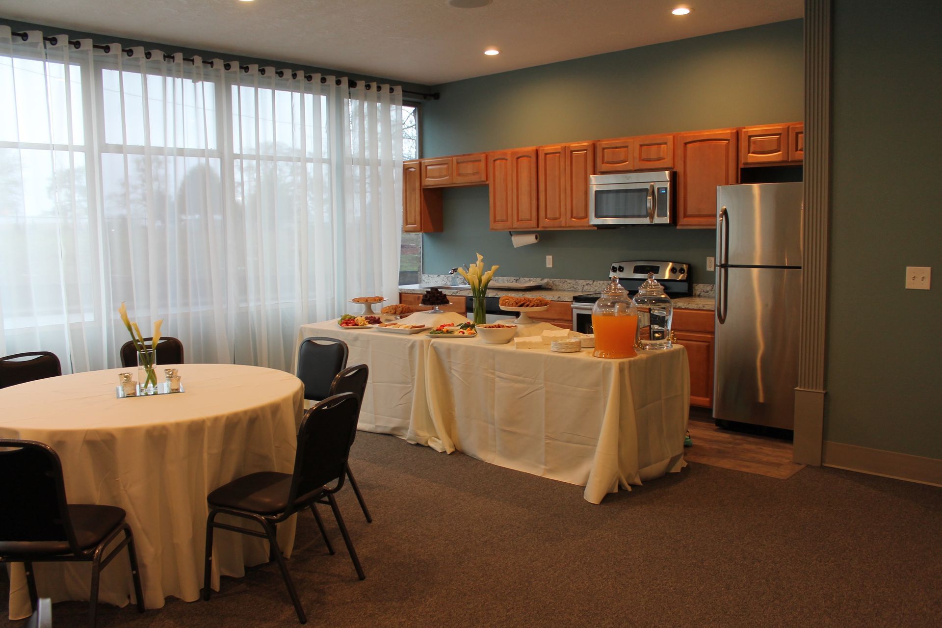 A kitchen with tables and chairs and a refrigerator