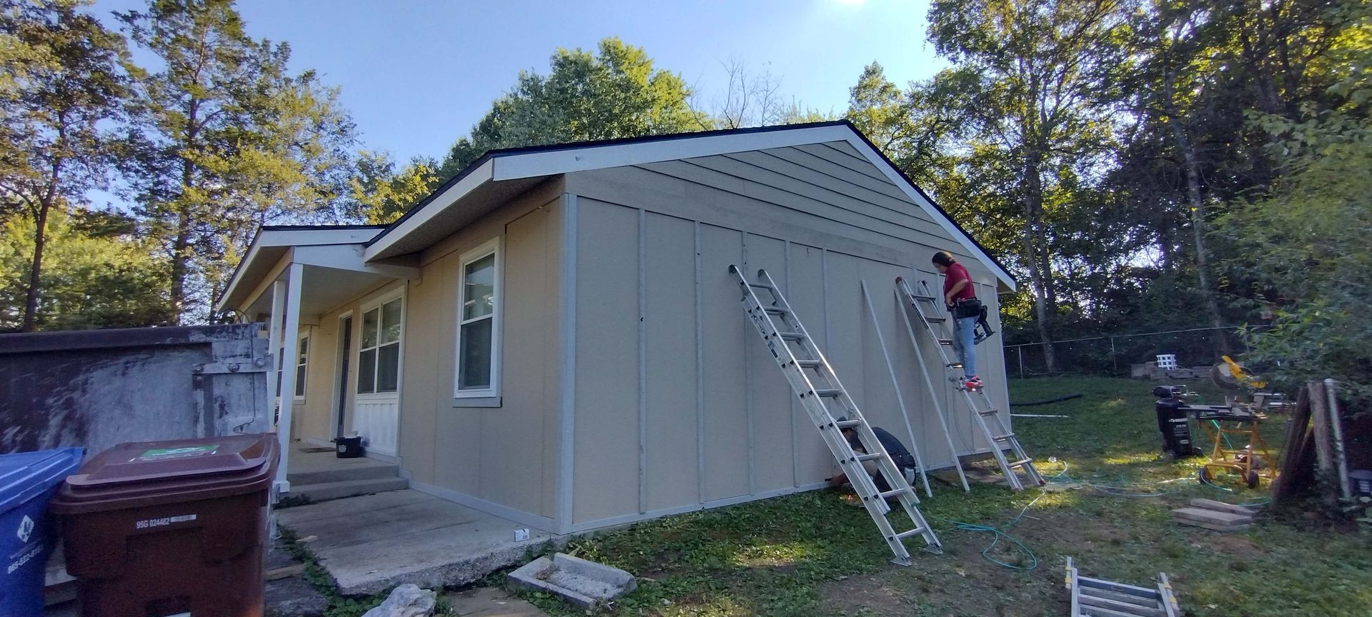 A man is standing on a ladder on the side of a house.