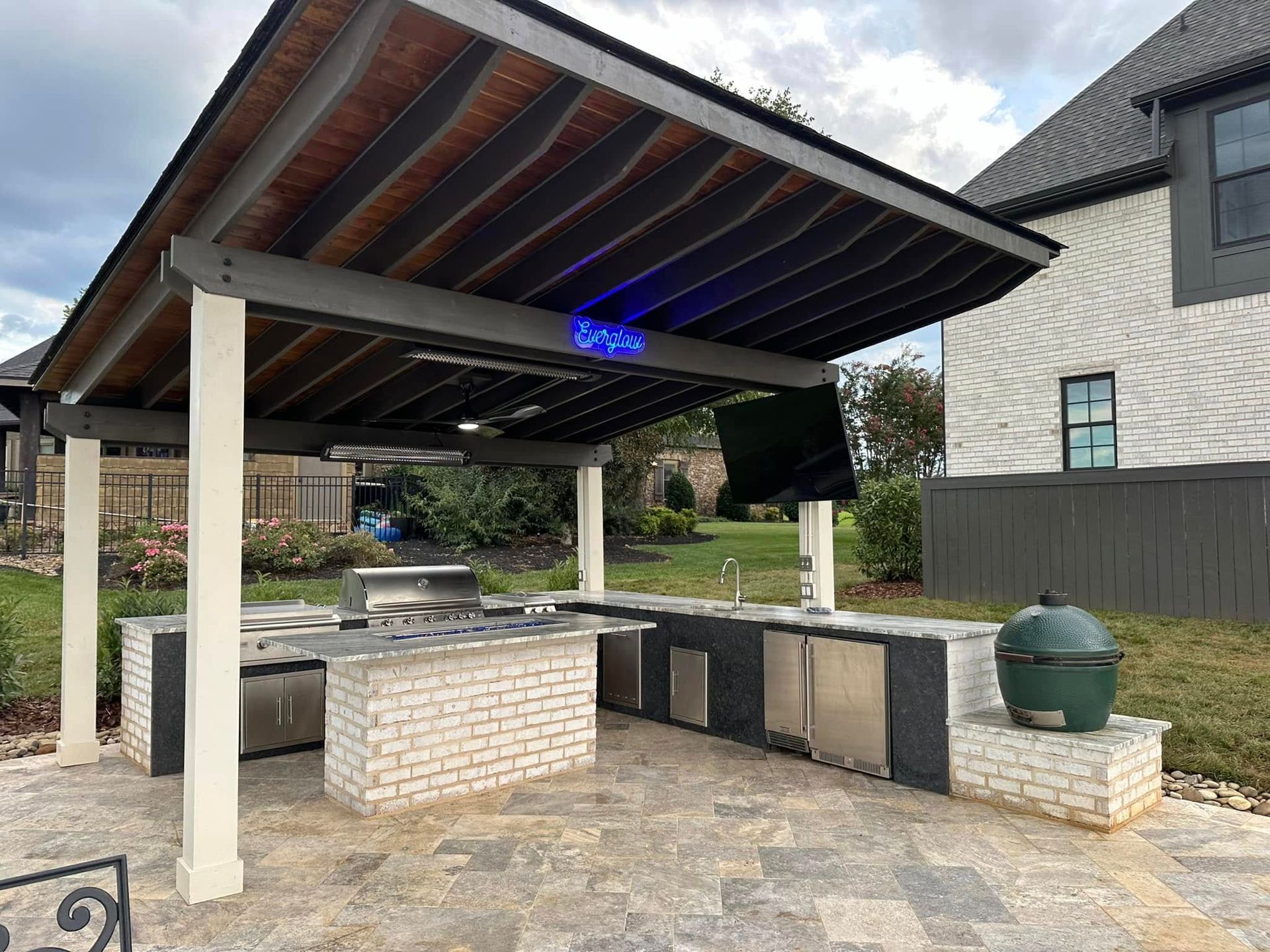 A large outdoor kitchen with a large green egg in the backyard.