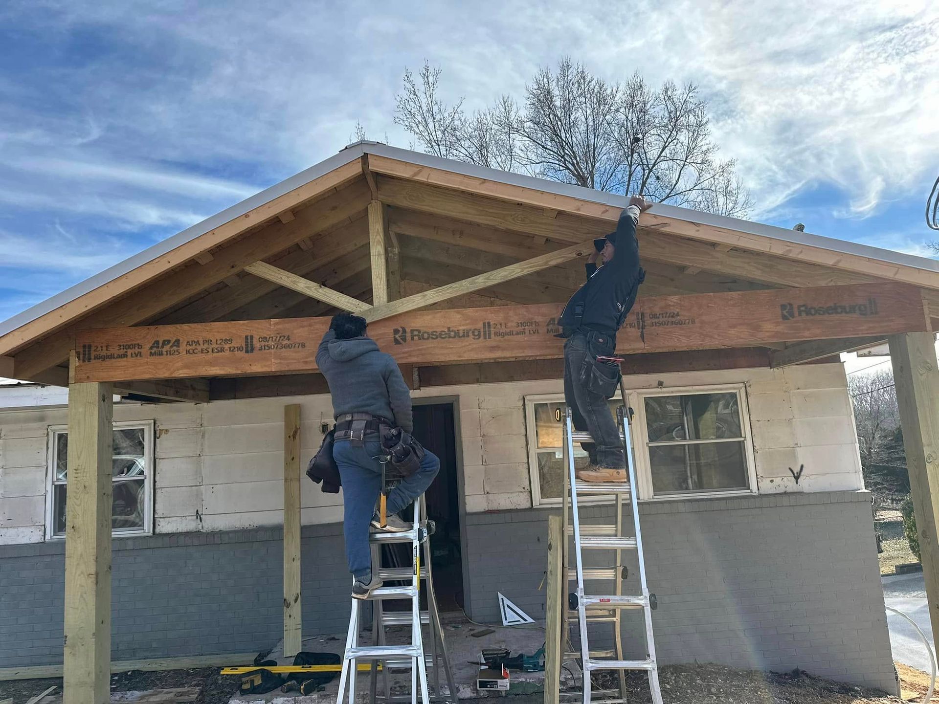 Two men are working on the roof of a house.