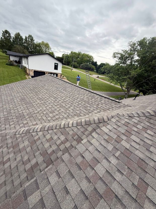 A man is standing on the roof of a house.