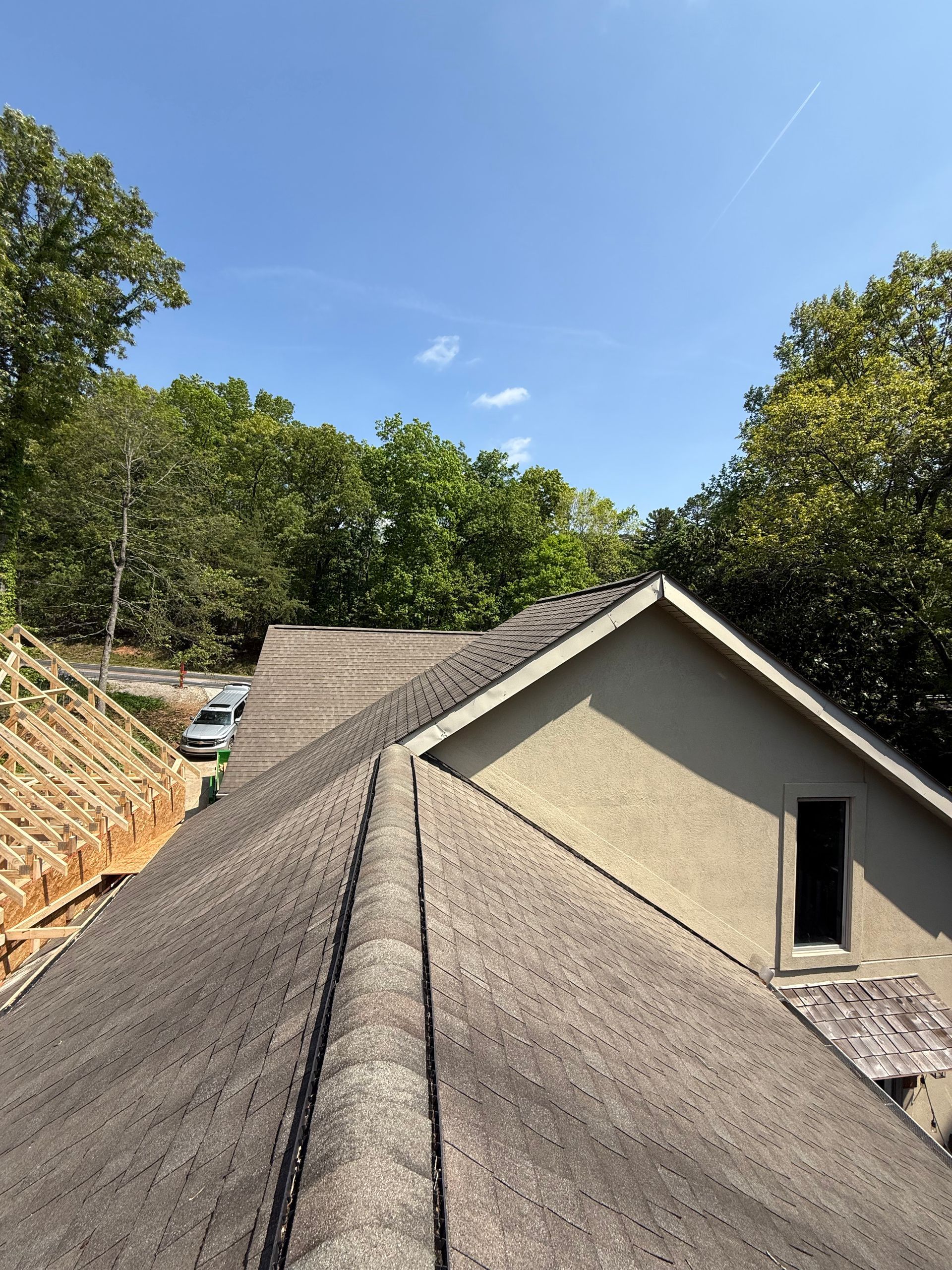 A roof of a house with a blue sky and trees in the background.