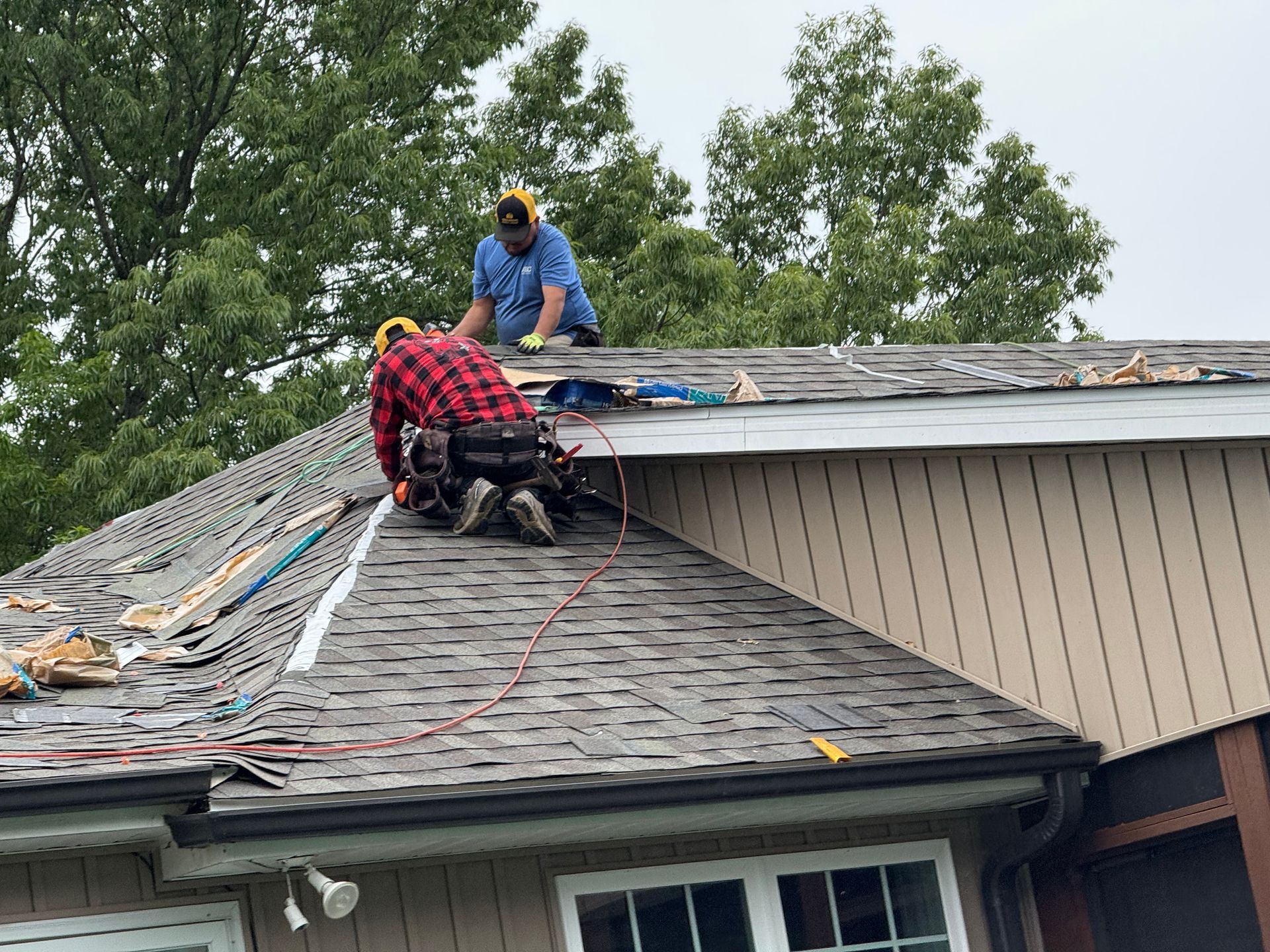 Two men are working on the roof of a house.