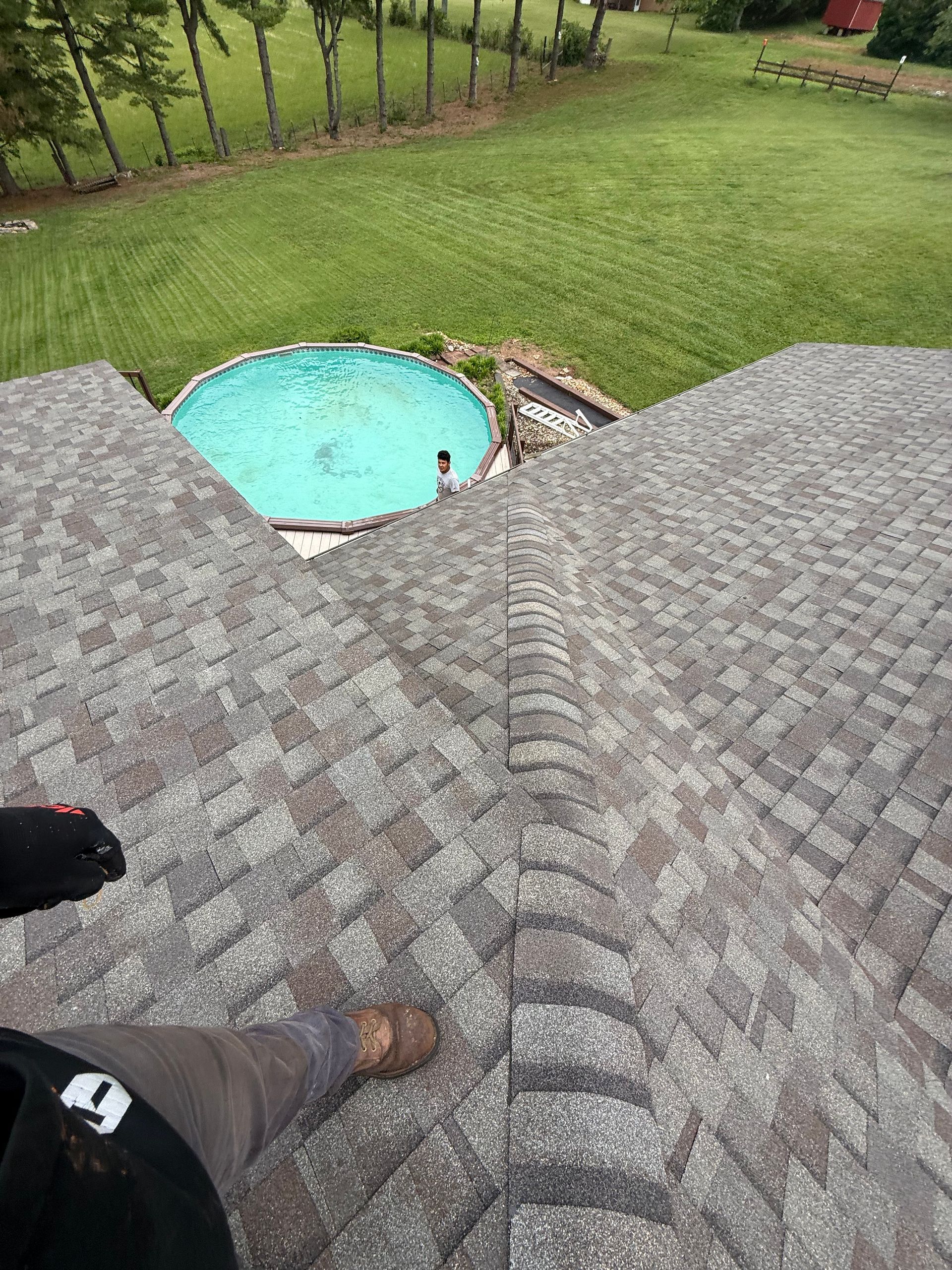 A person is standing on top of a roof next to a pool.