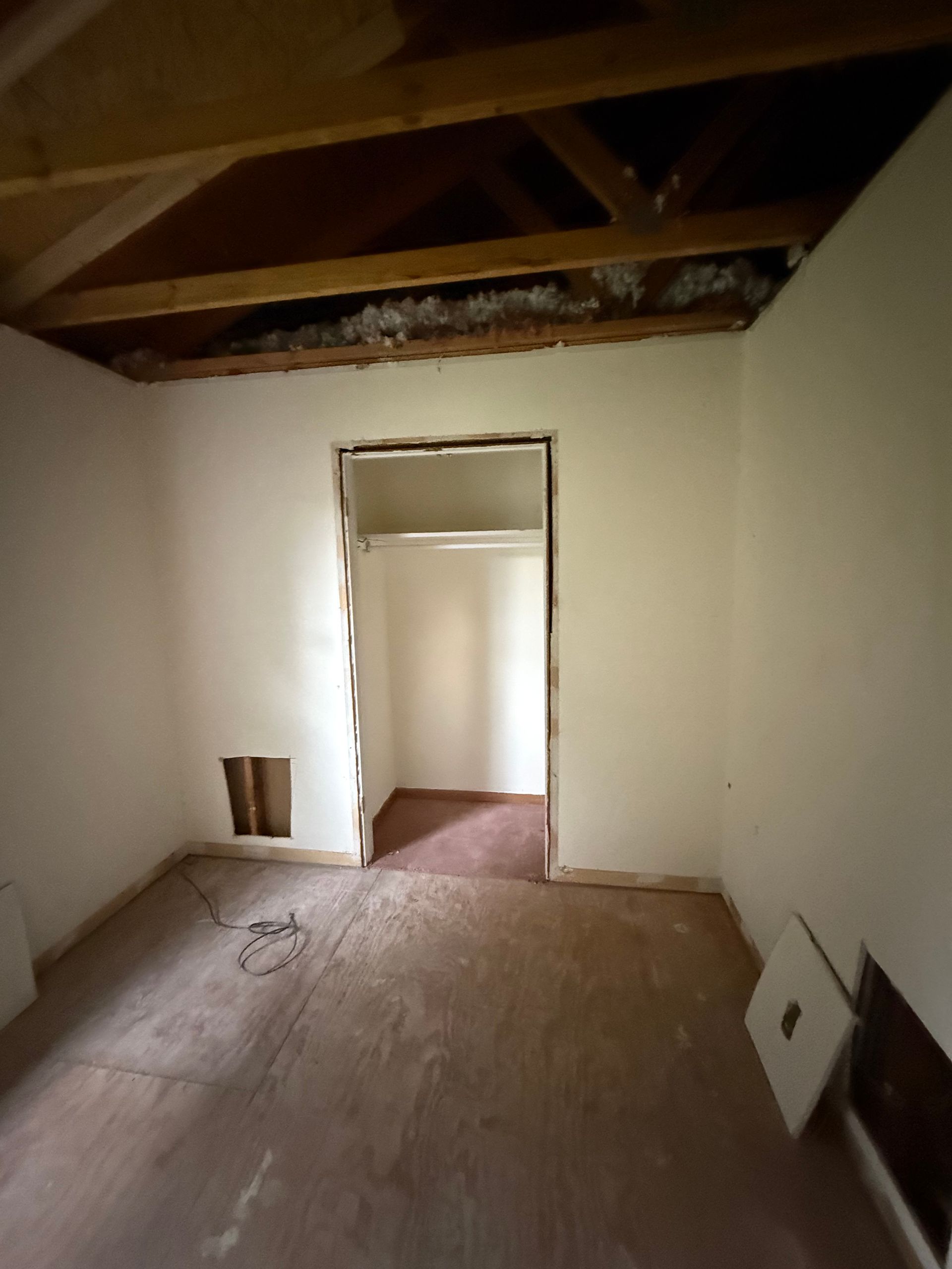 An empty room with a doorway leading to a closet