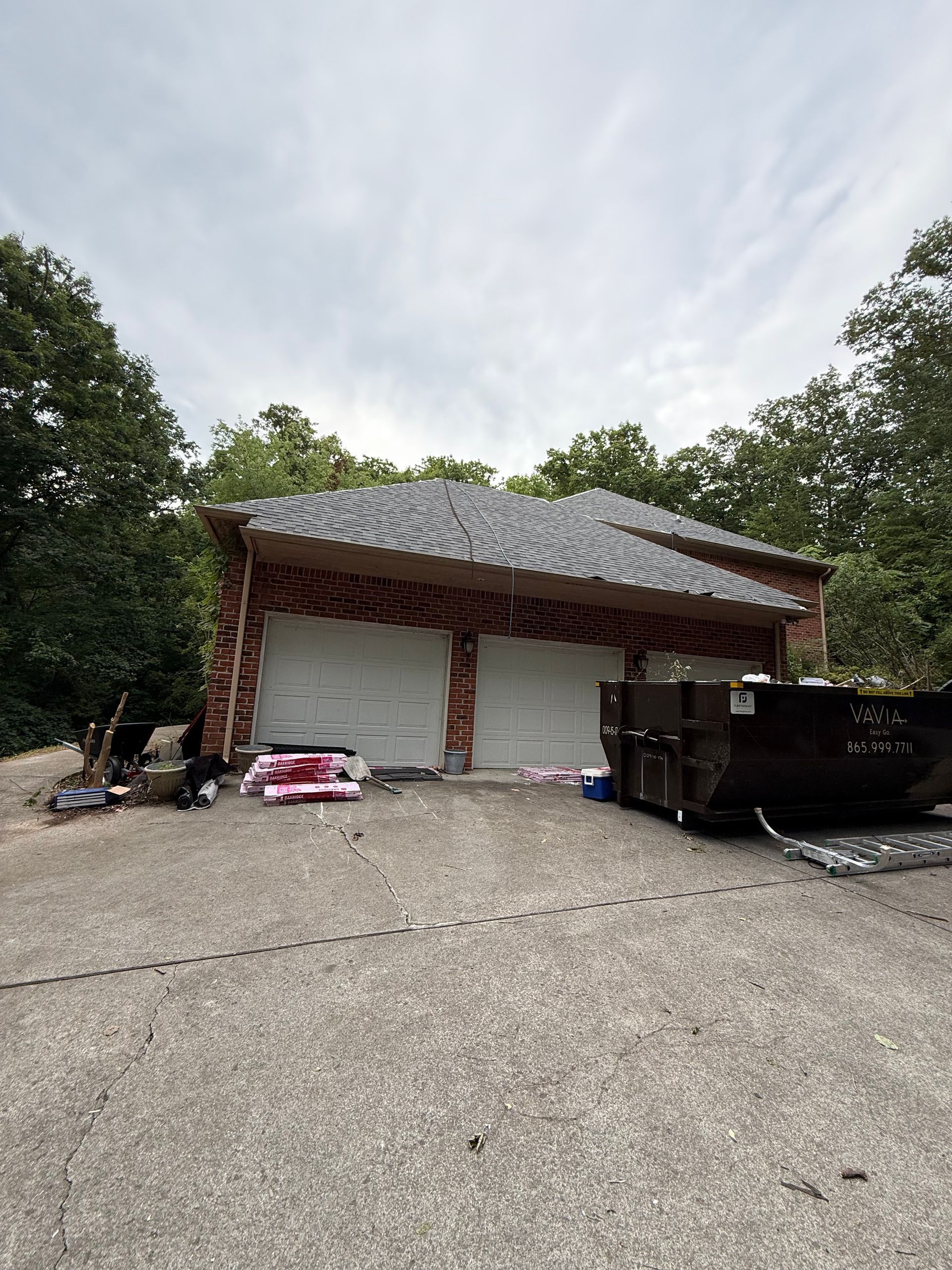 A garage with two garage doors and a dumpster in front of it.
