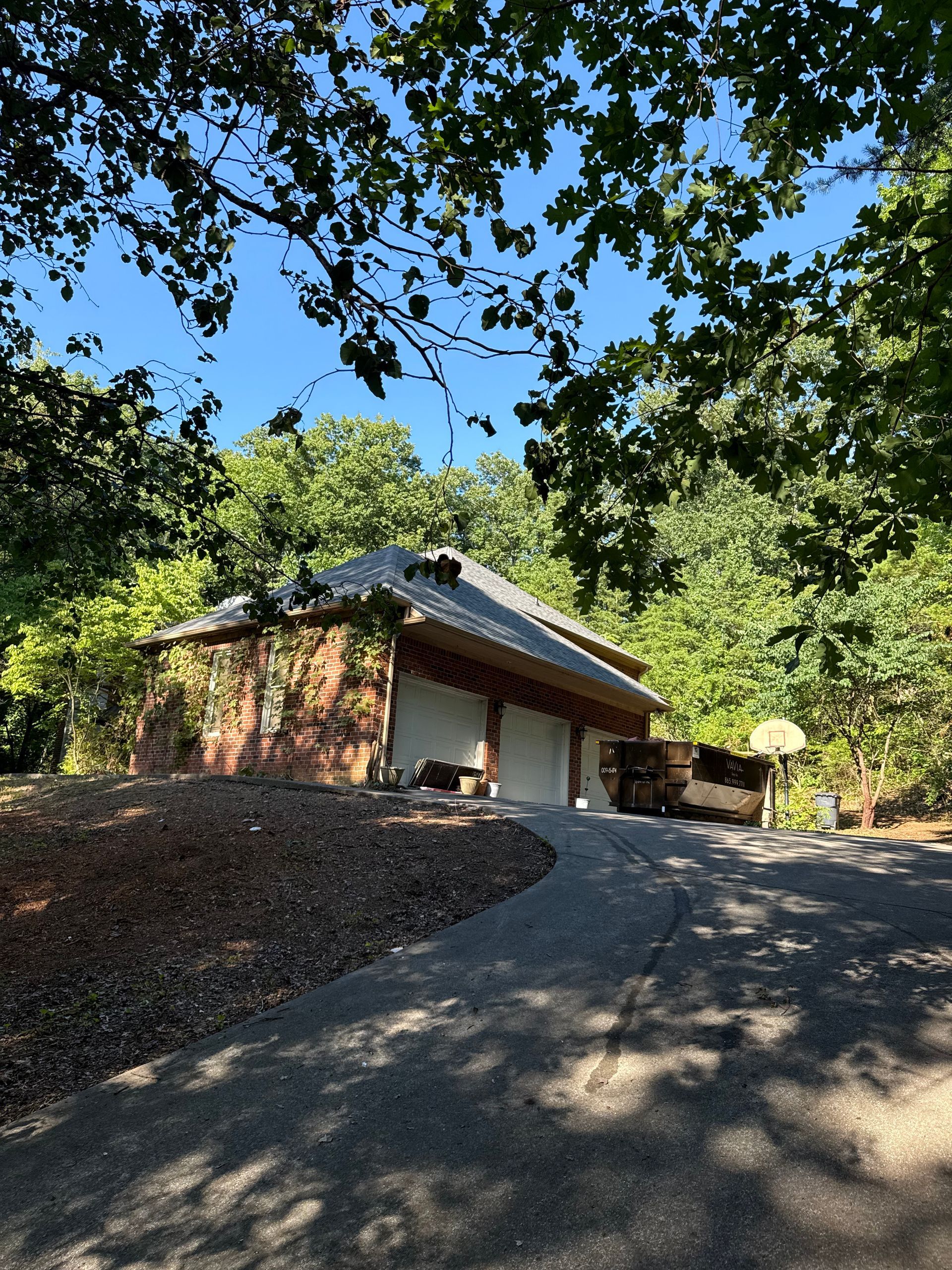 A brick house is surrounded by trees and a driveway