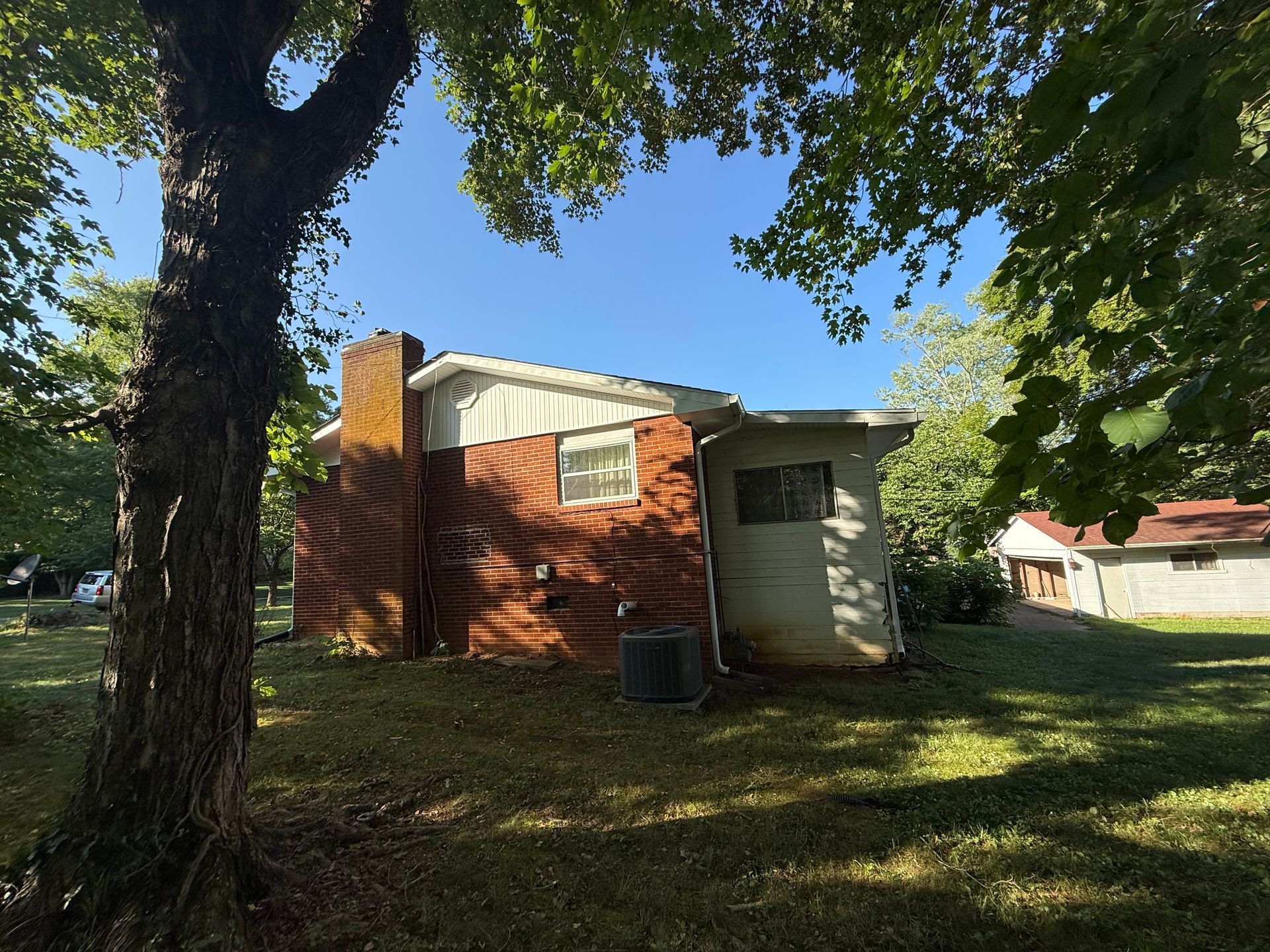 A small brick house with a tree in front of it