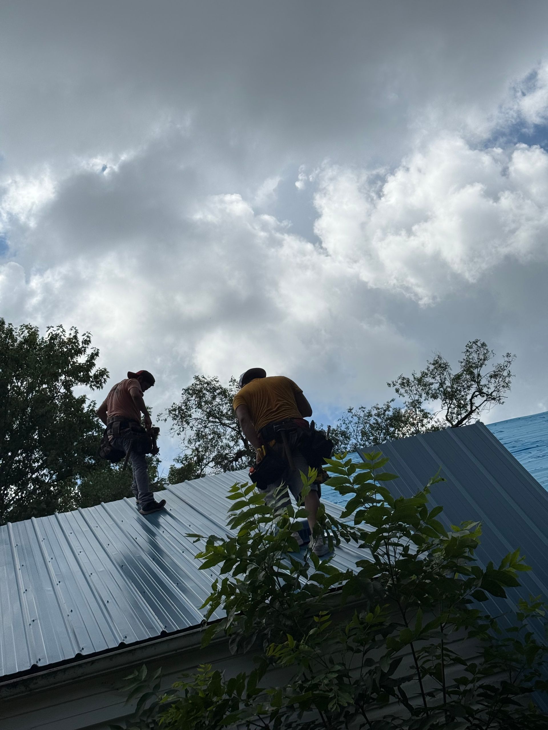 Two men are working on the roof of a house.