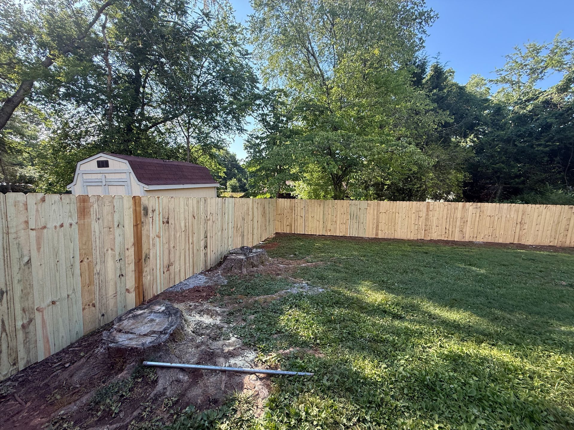 A wooden fence is surrounding a lush green yard.