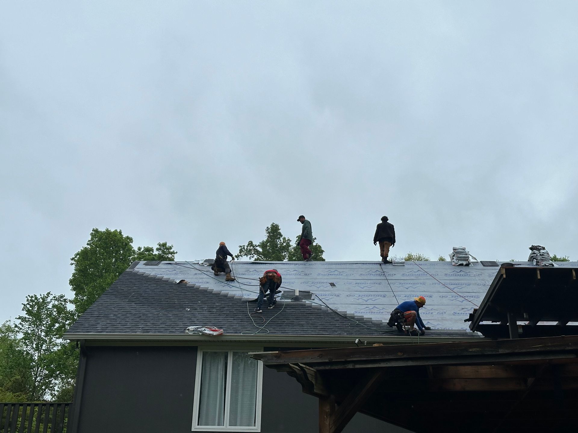 A group of people are working on the roof of a house.