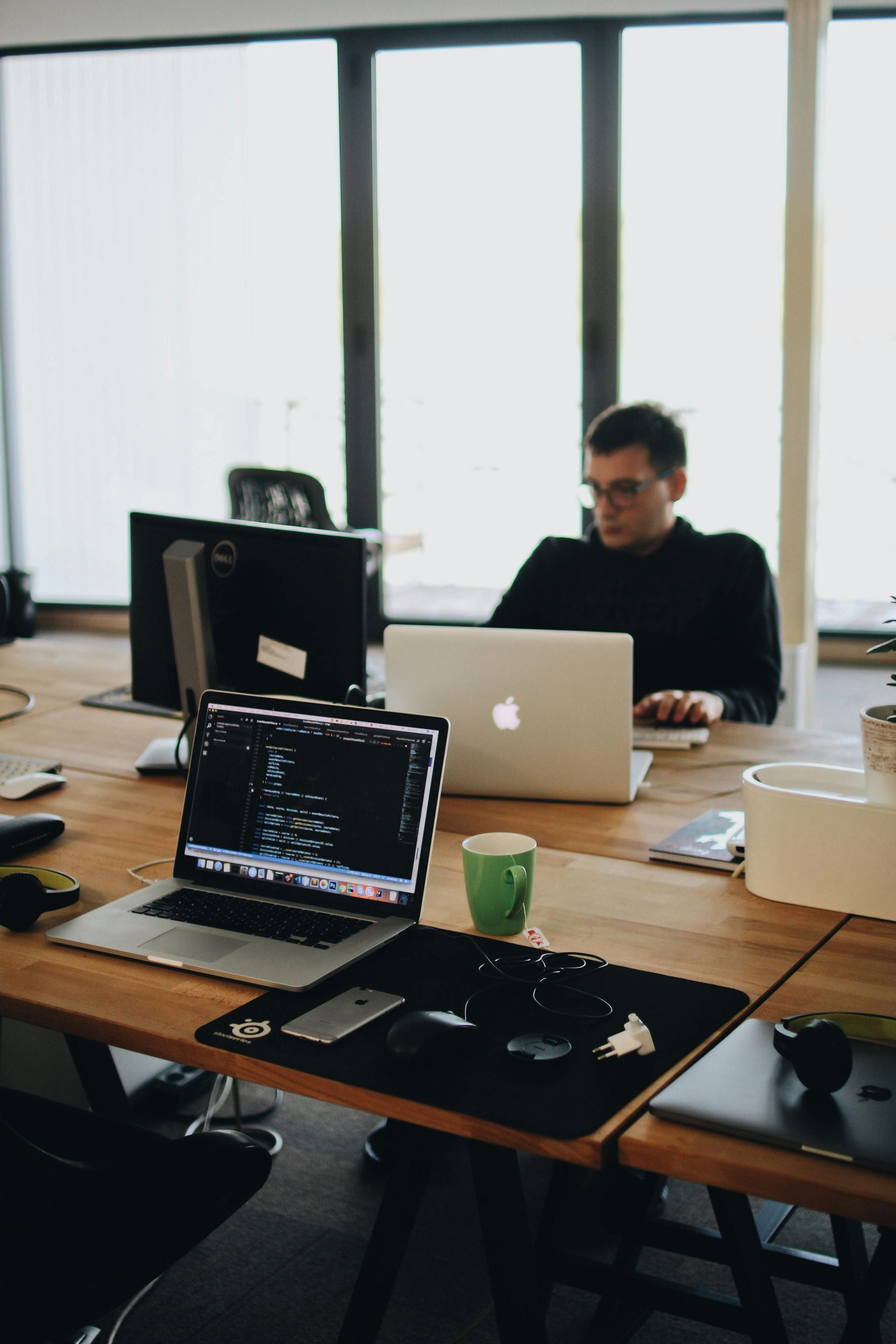 Un homme est assis à un bureau avec deux ordinateurs portables dessus.