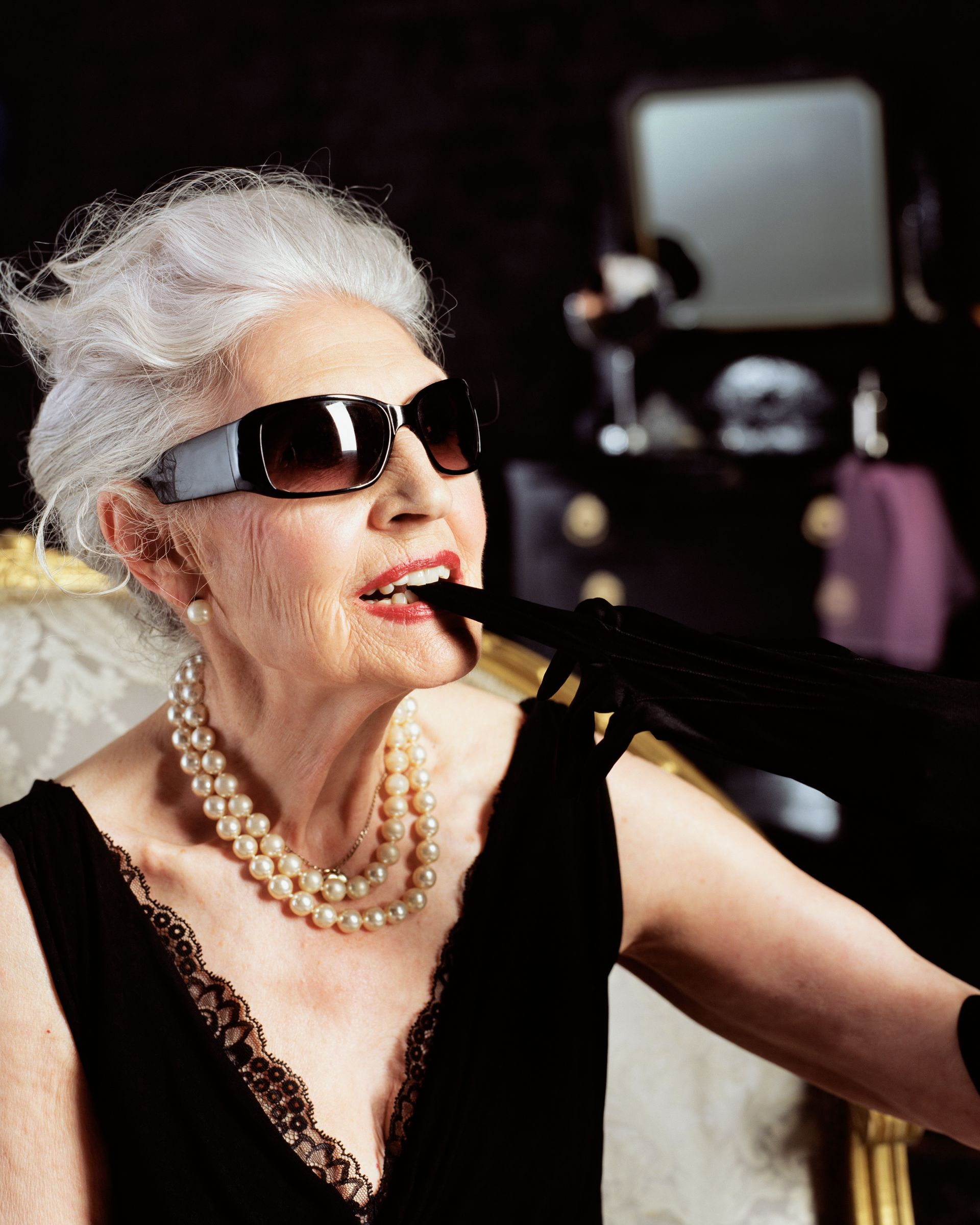 Una donna anziana che indossa occhiali da sole e una collana di perle