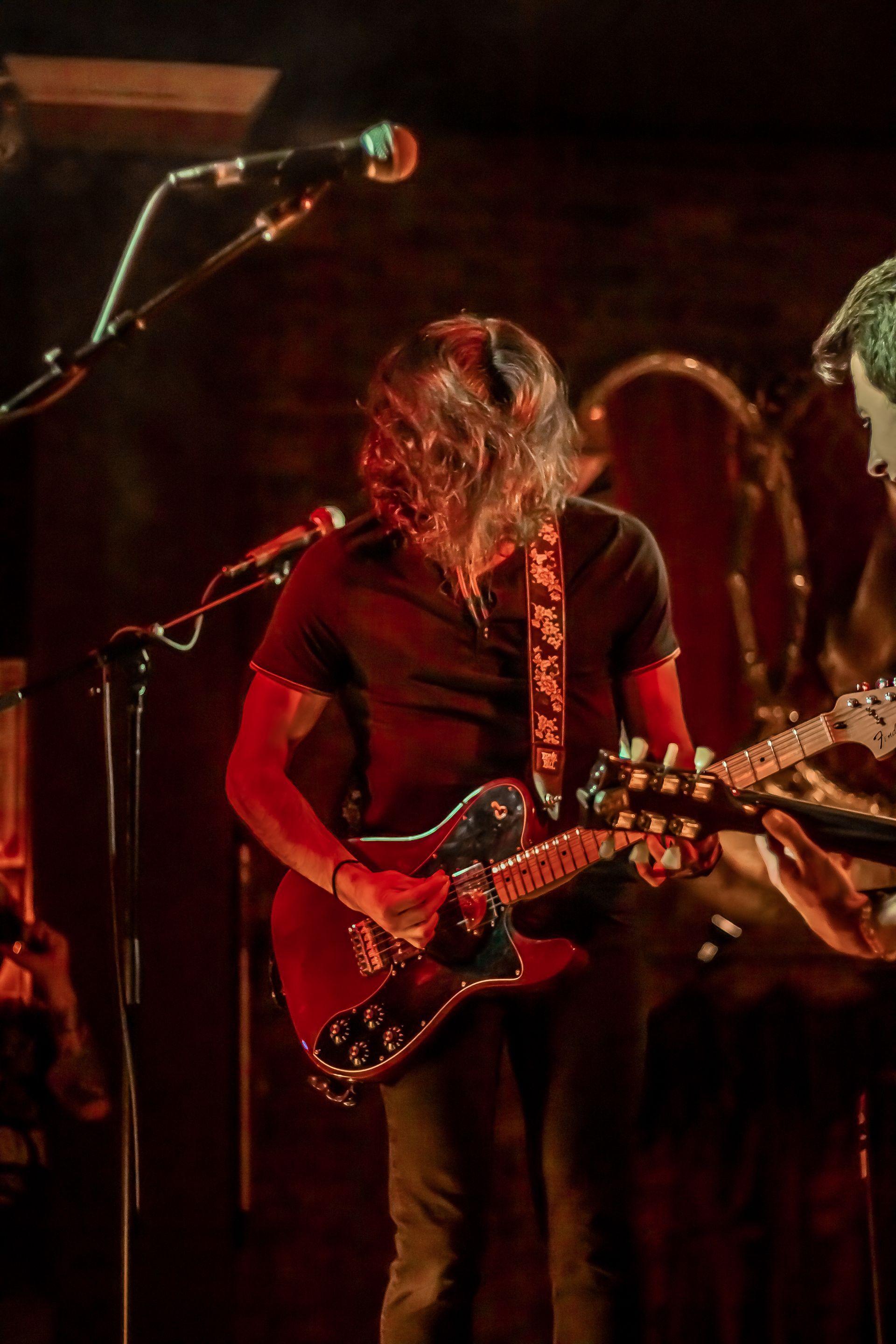 A man is playing a guitar and singing into a microphone on a stage.
