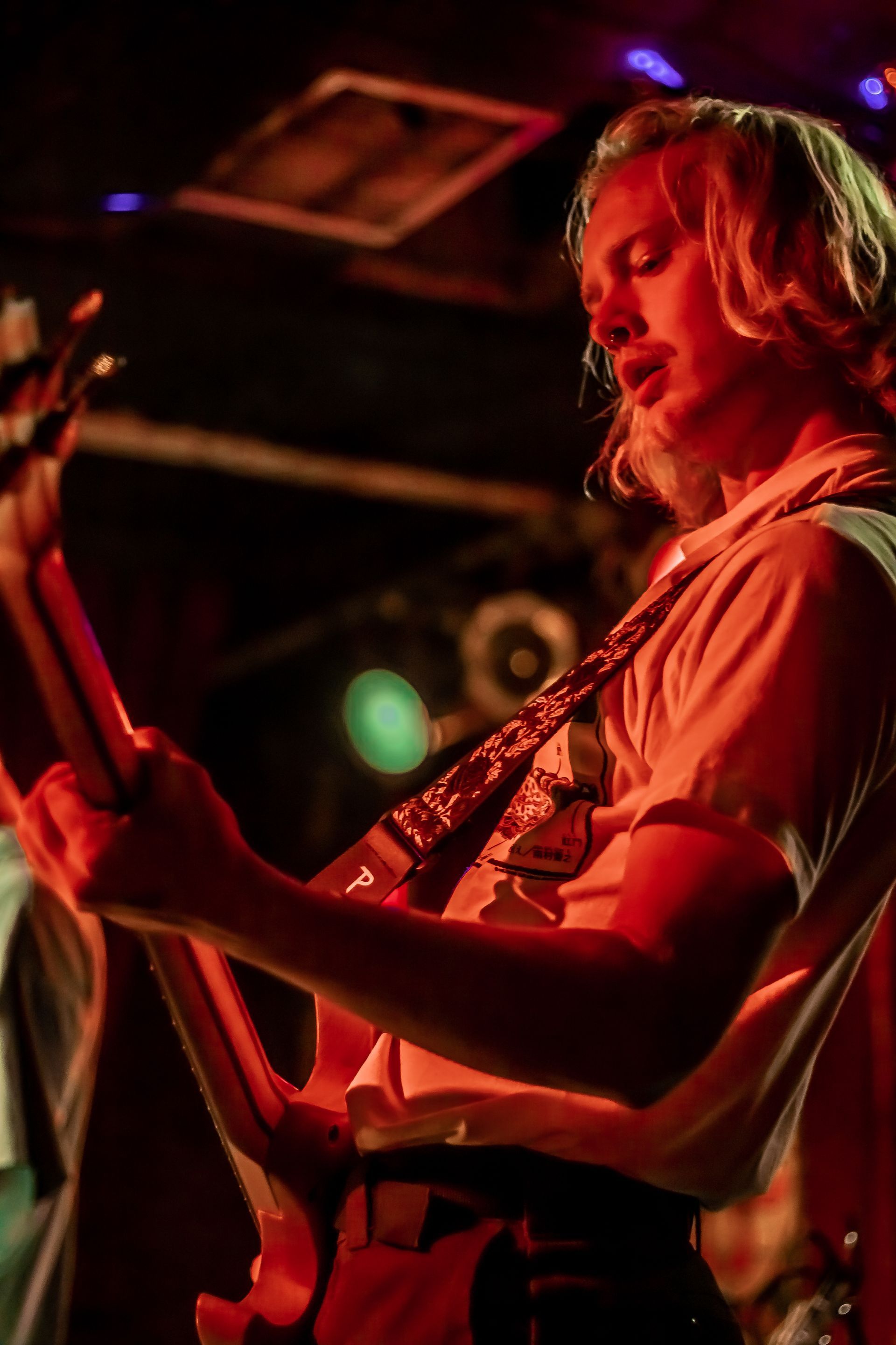 A man is playing a guitar on stage in a dark room.