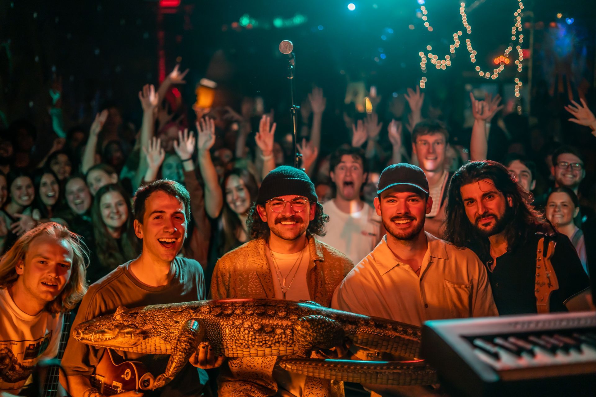 A group of people standing around a statue of a crocodile in front of a crowd.