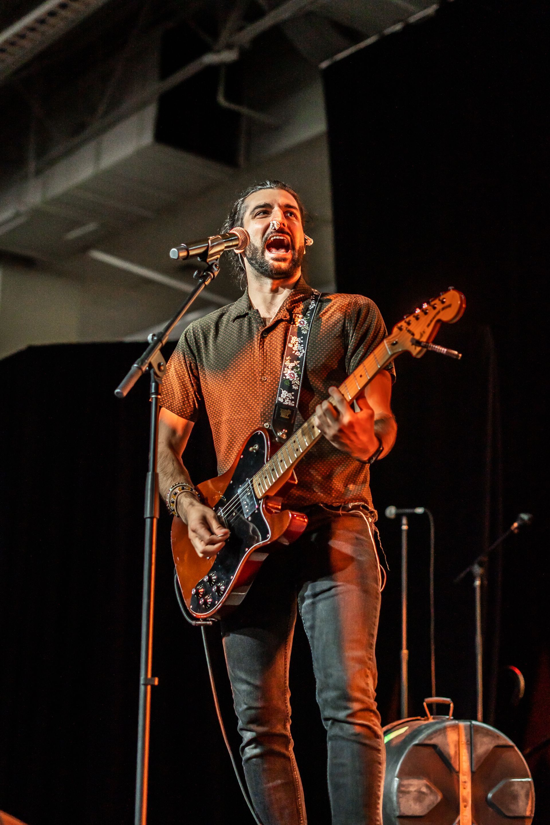 A man is playing a guitar and singing into a microphone on a stage.
