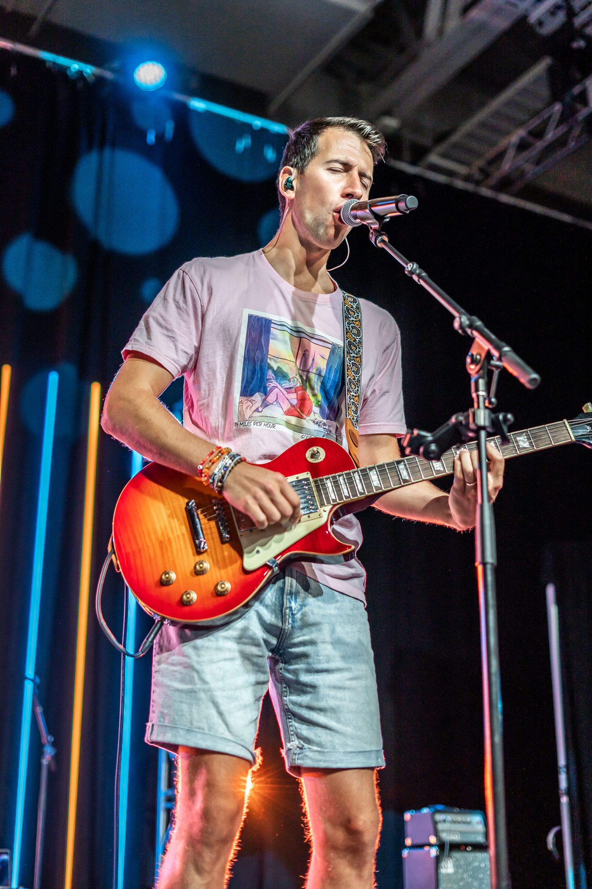 A man is playing a guitar and singing into a microphone on a stage.