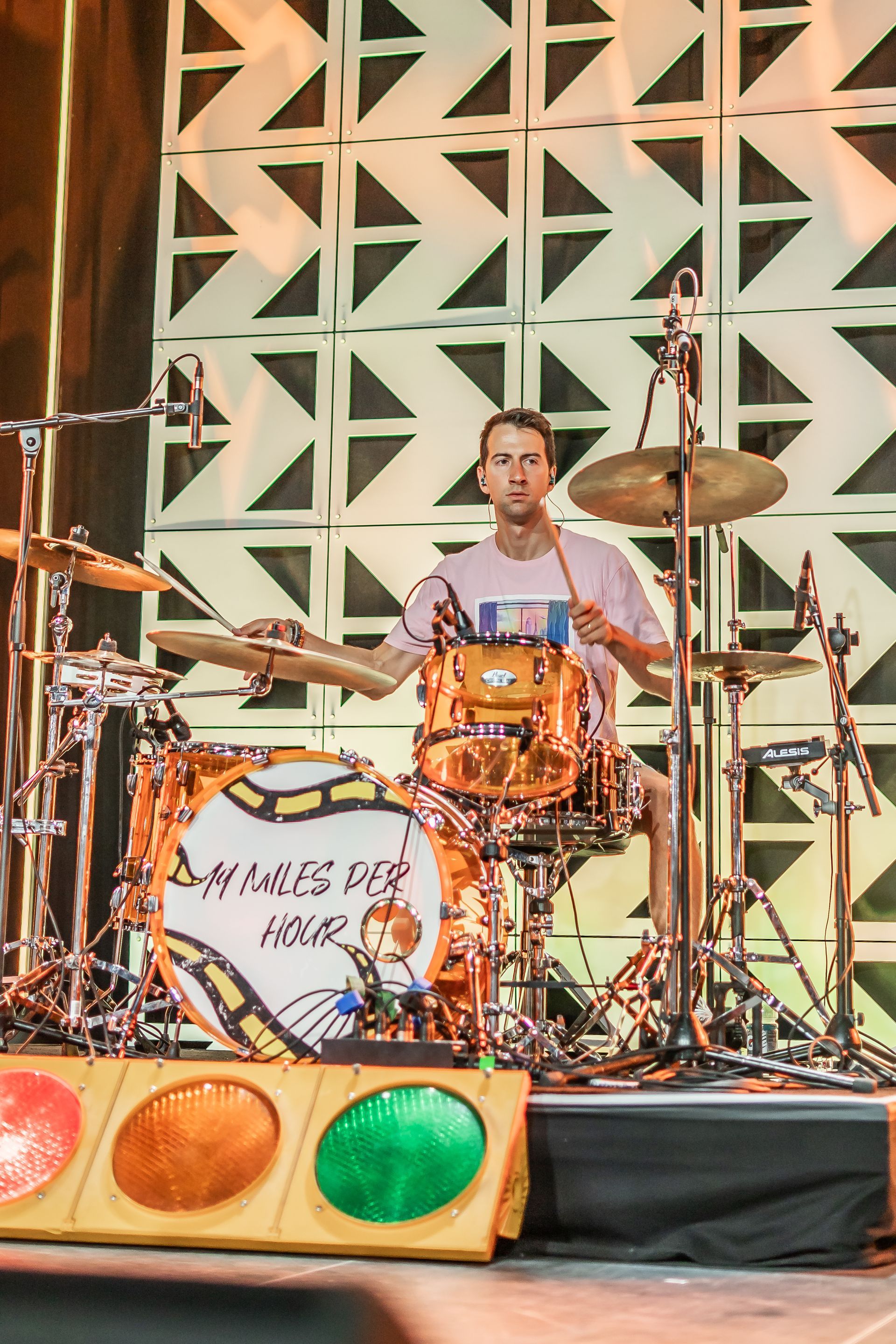 A man is playing drums in front of a drum set that says drums for hour