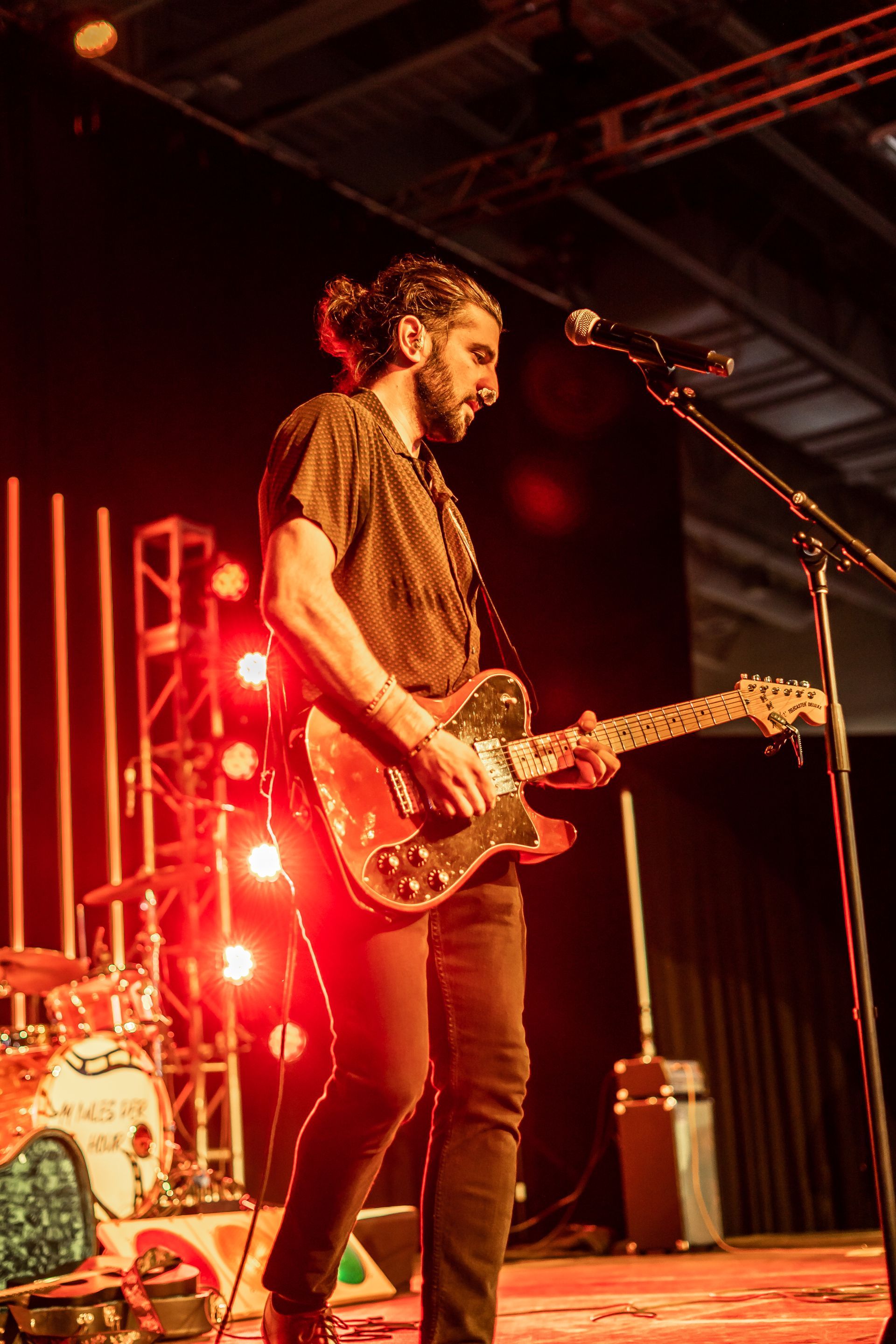 A man playing a guitar and singing into a microphone on a stage