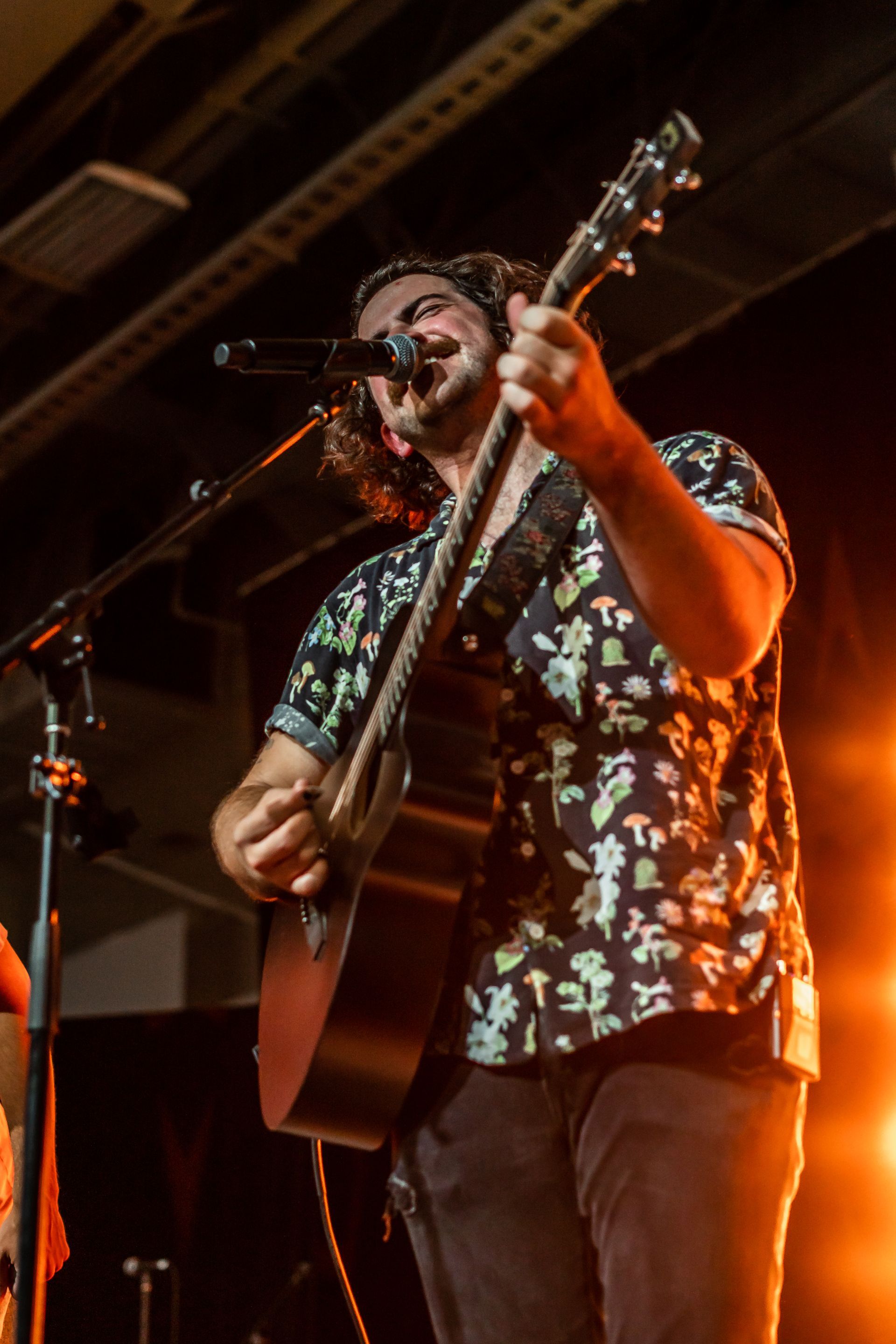 A man is playing a guitar and singing into a microphone on a stage.