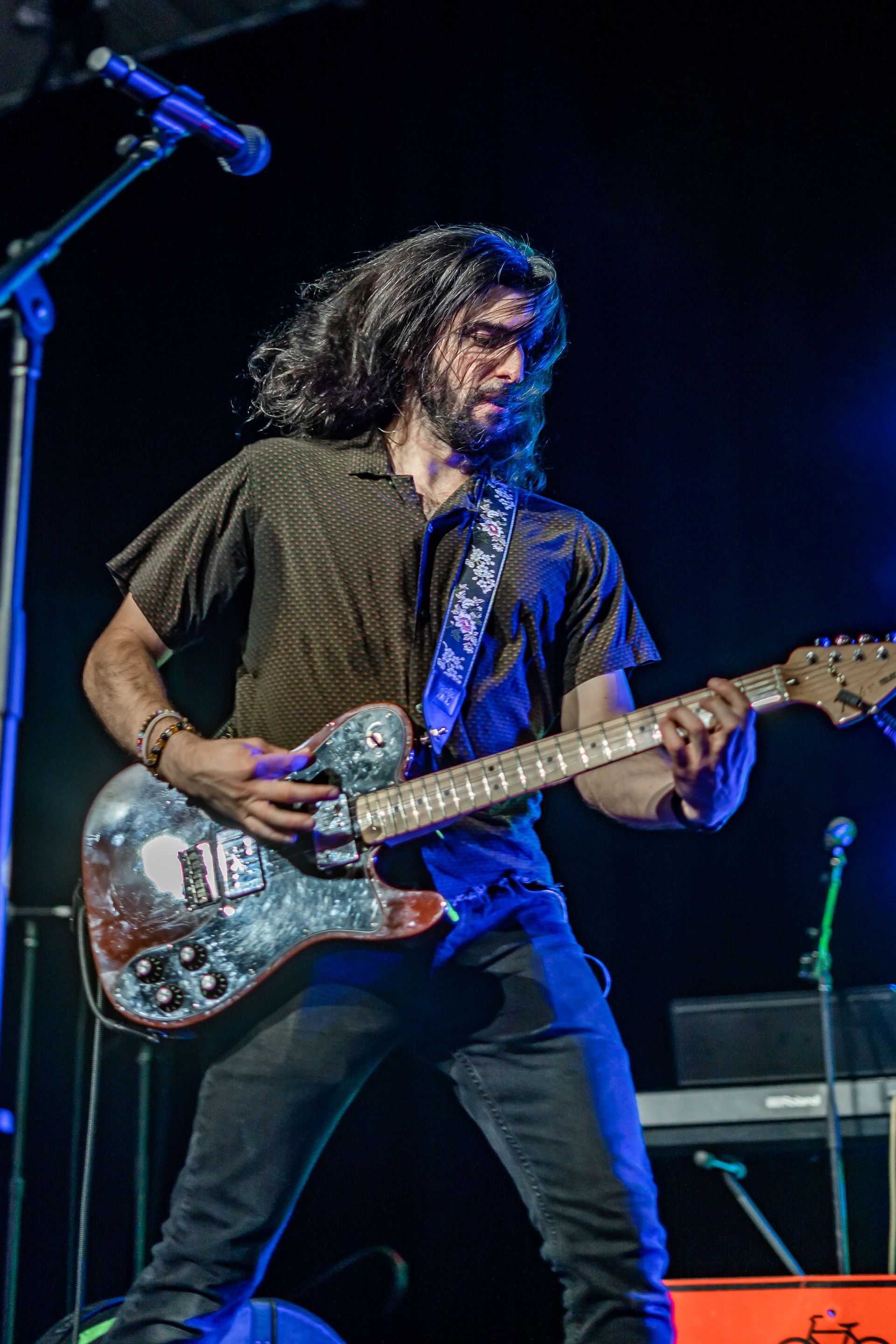 A man is playing a guitar on stage in front of a microphone.