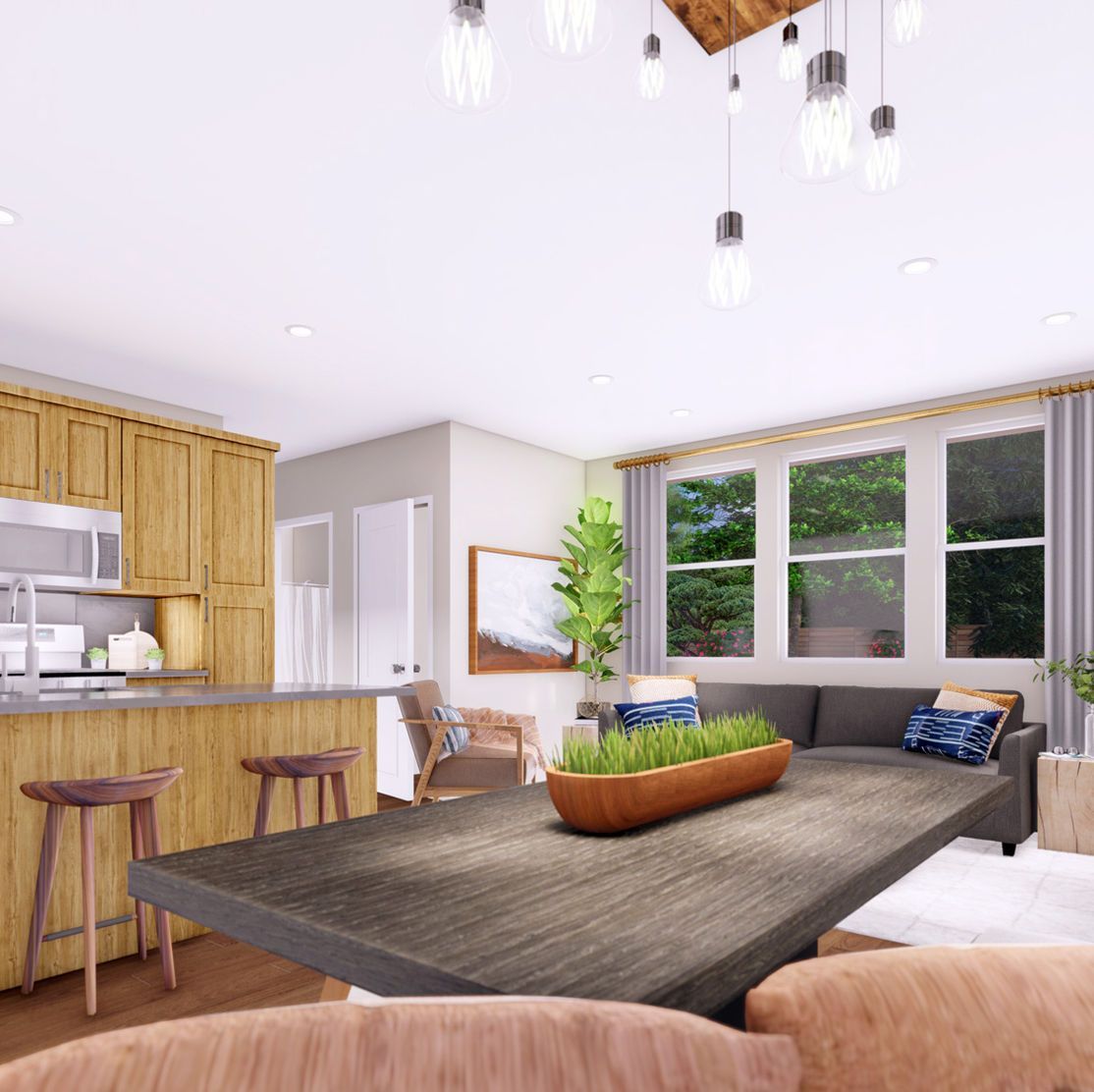 Open-concept living space with kitchen and dining area; wood cabinetry, gray sofa, rustic table.