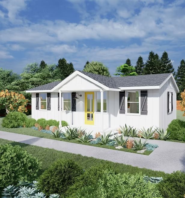 White house with yellow door, dark shutters, and gray roof. Landscaping in front.