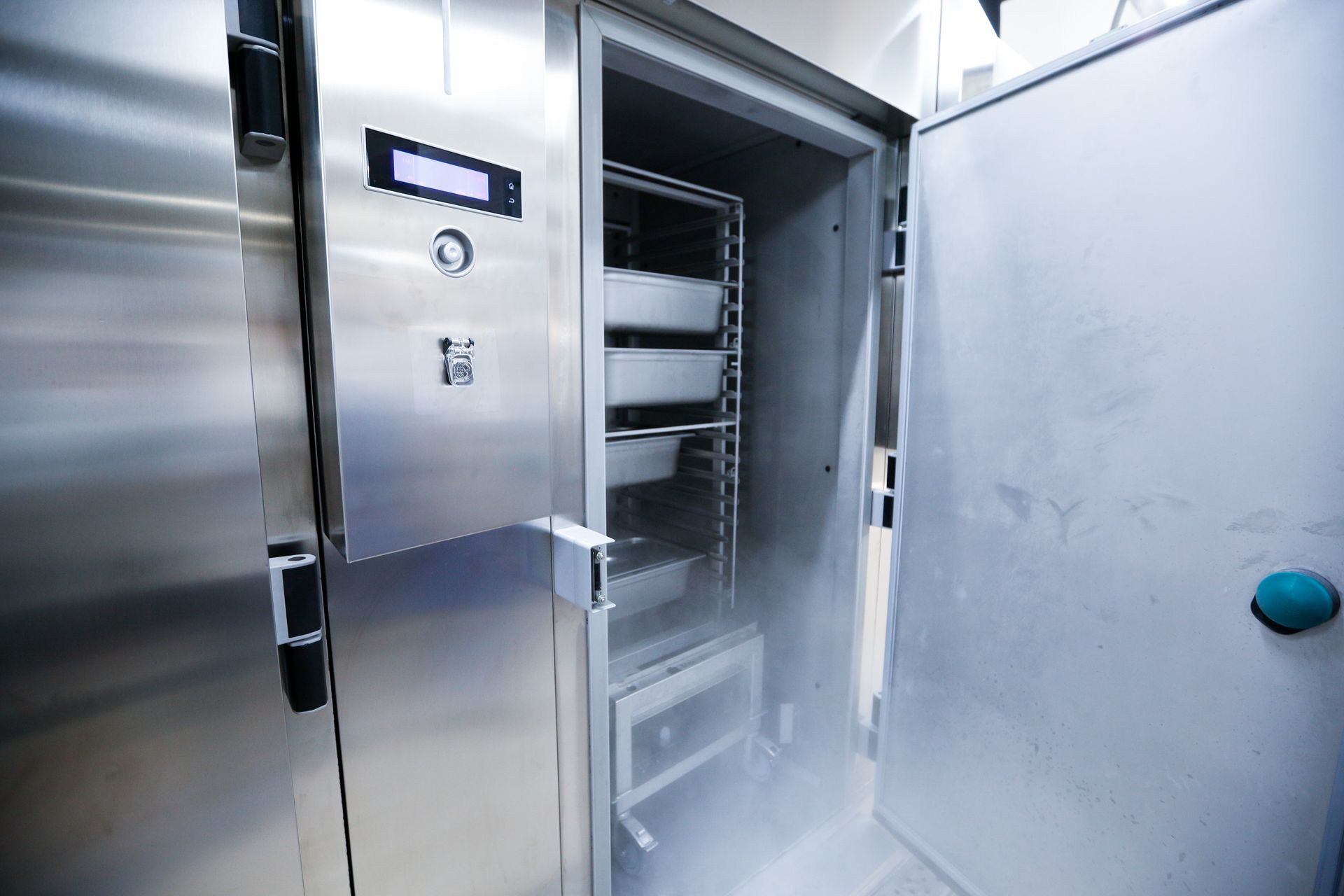 Open stainless-steel walk-in freezer with metal shelving inside