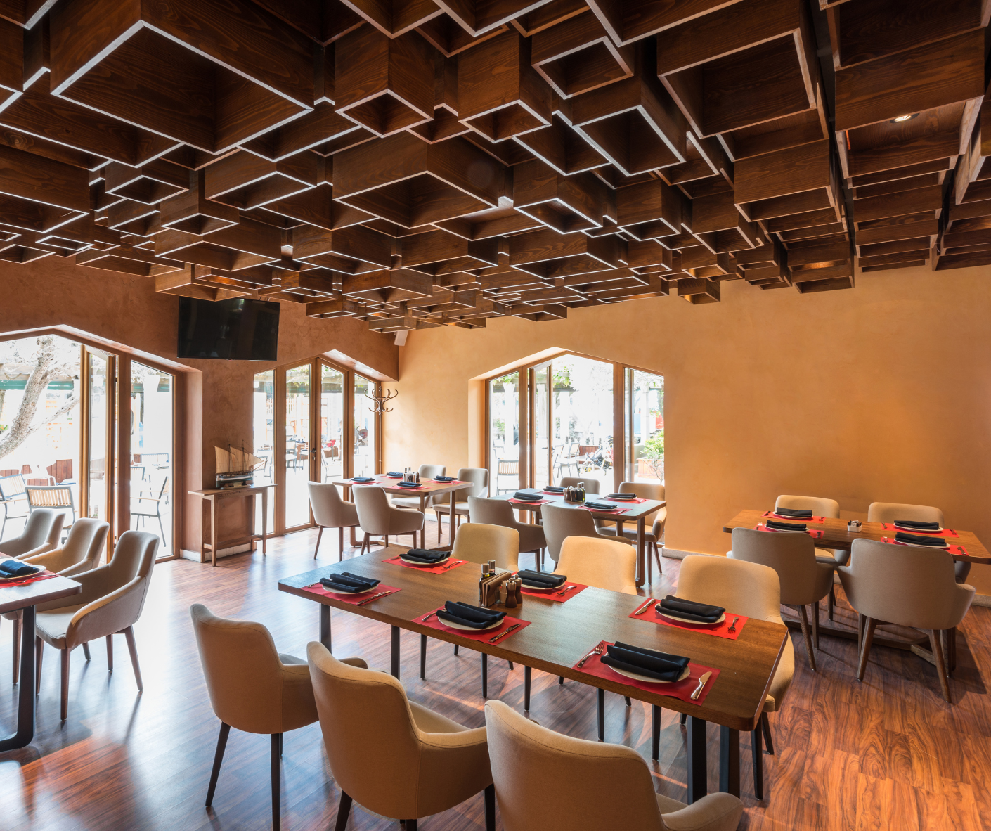 Modern restaurant dining room with wood lattice ceiling, tables, and chairs by large windows Modern restaurant dining room with wood lattice ceiling, tables, and chairs by large windows