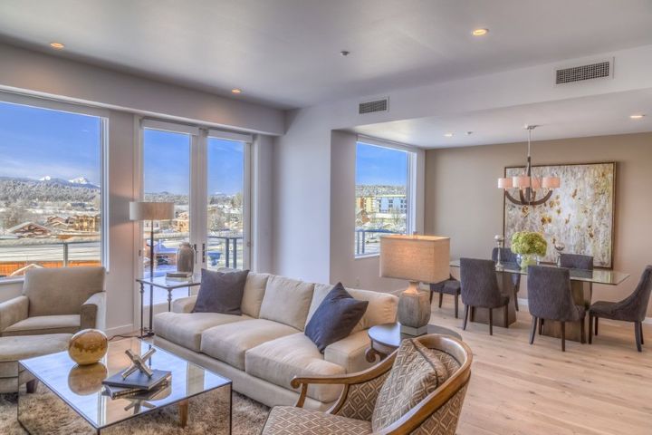 Picture of an open area of a living room and dining room with big glass windows on the back.