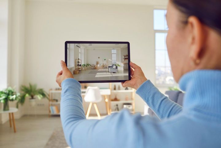 Woman taking picture of office area in a house with a tablet.