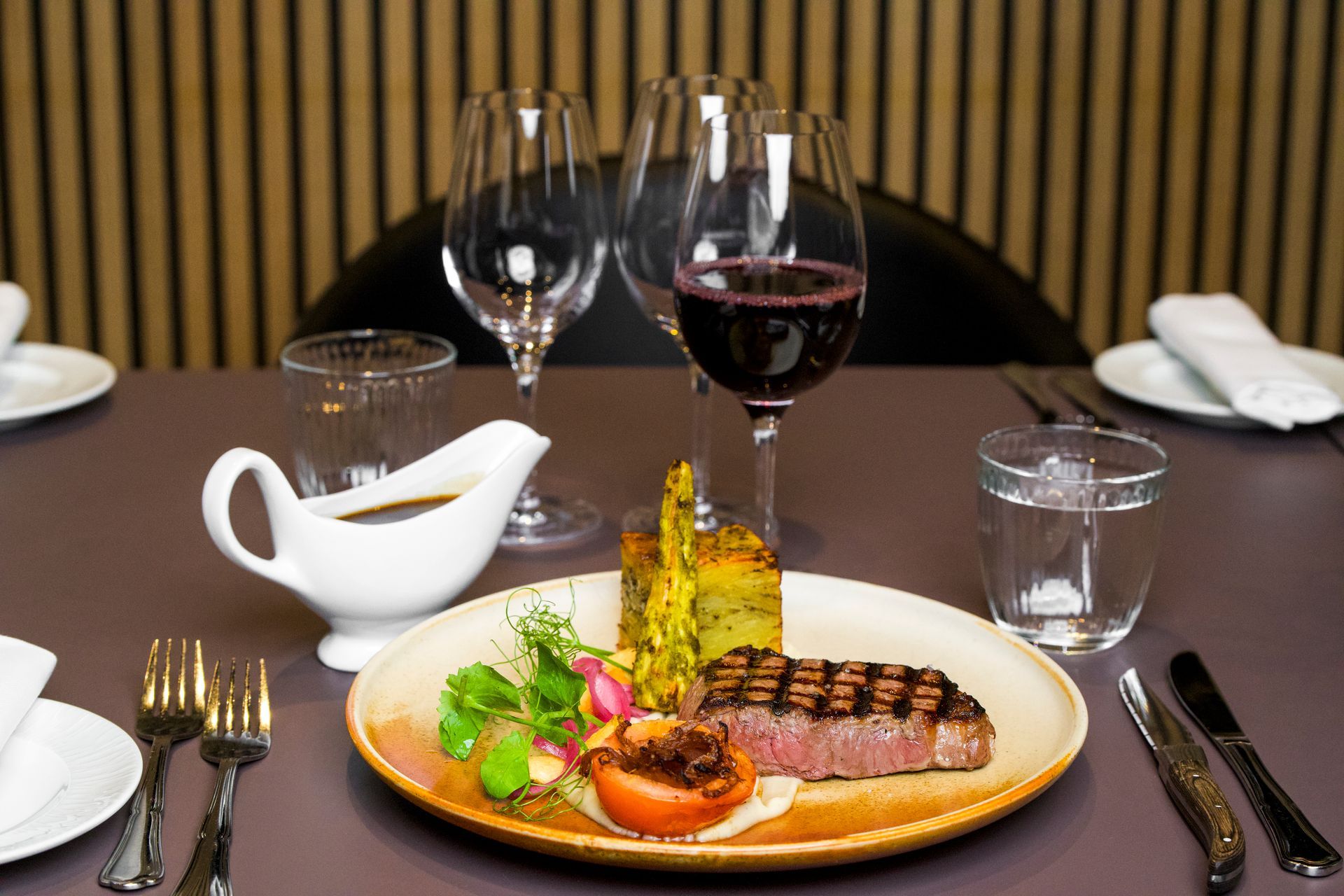Bøfmiddag med vin og tilbehør på et bord i en restaurant.