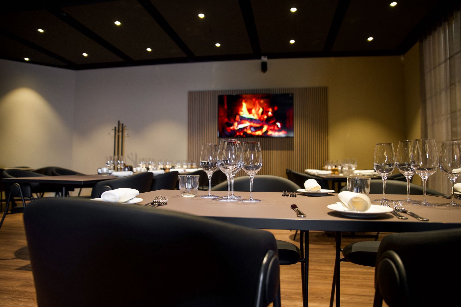 Elegant restaurantspisestue med dækkede borde, pejs på væggen og mørke stole.