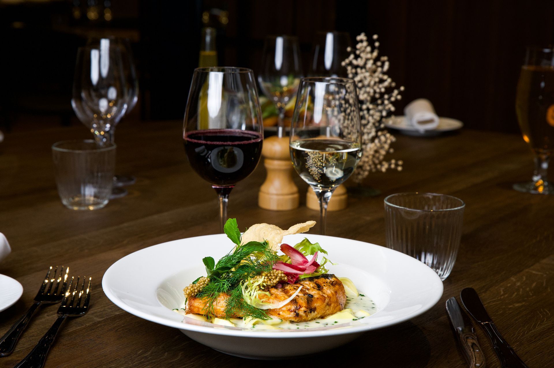 Tallerken med mad med vinglas på et træbord i en restaurant.