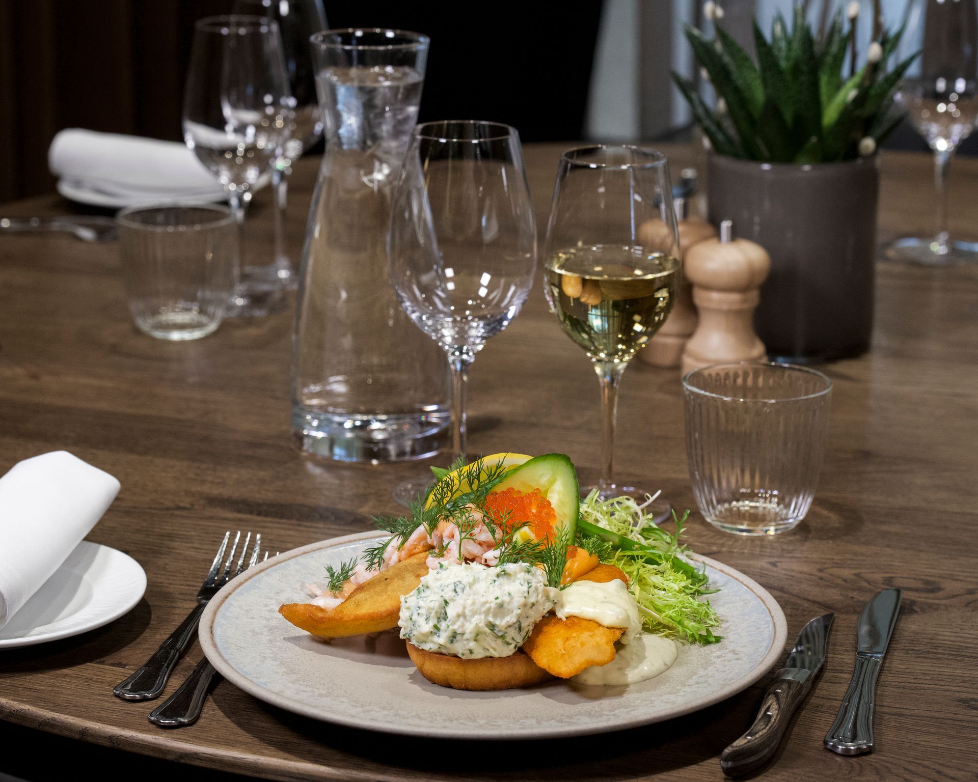 Tallerken med mad med vinglas på et træbord; fin spisestue.