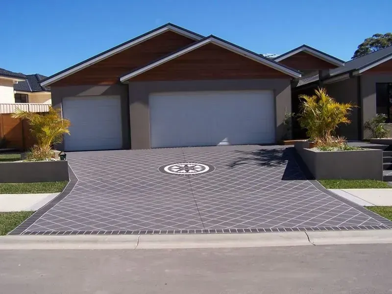 A driveway leading to a house with the letter g on it — Concrete Colour Solutions in Morisset, NSW