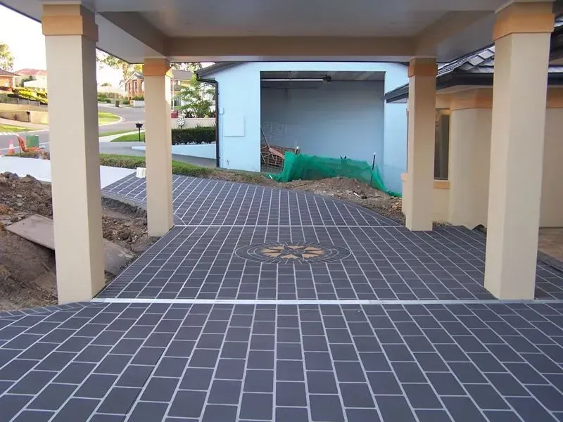 A brick driveway leading to a blue house — Concrete Colour Solutions in Morisset, NSW