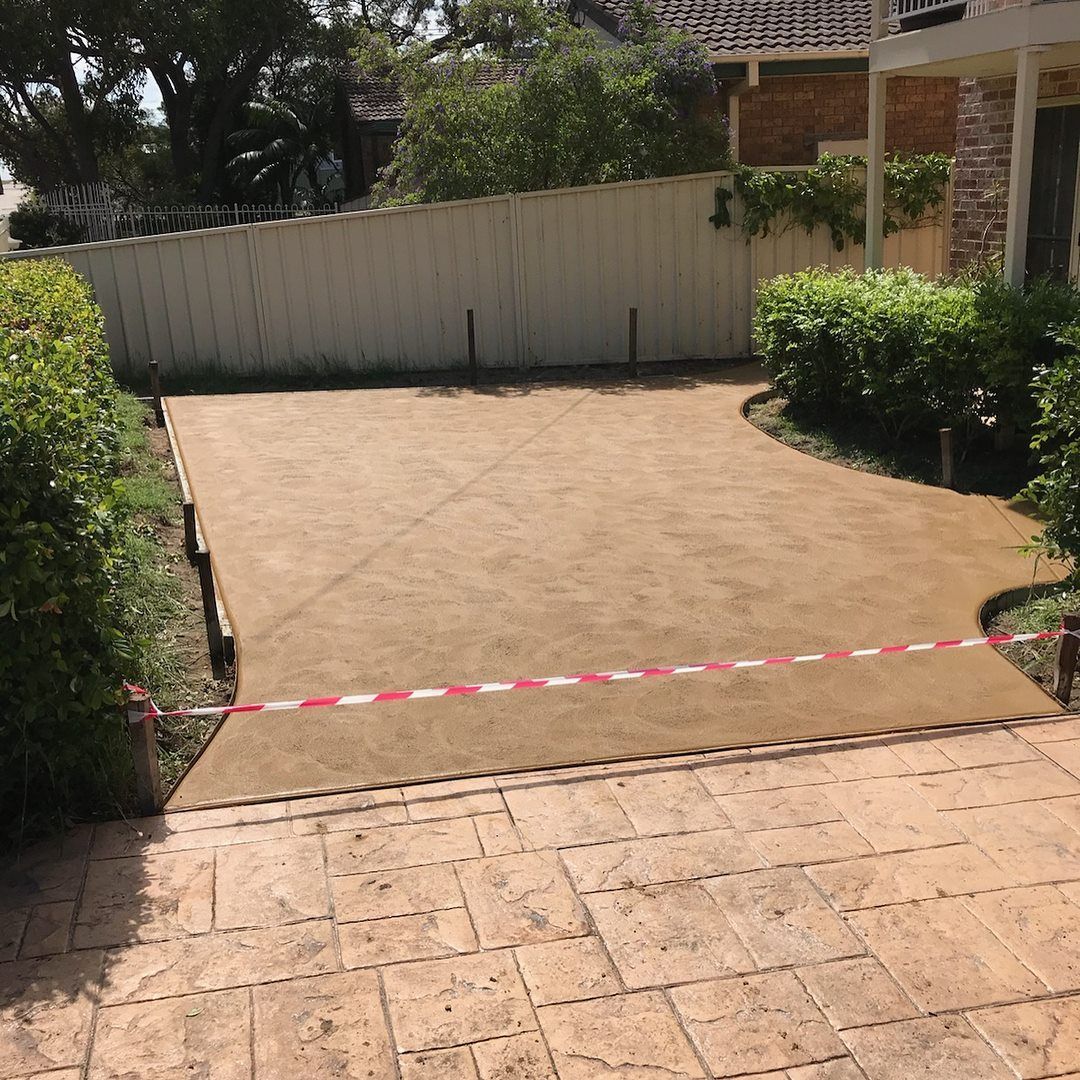 A Concrete Driveway with A White Fence in The Background — Concrete Colour Solutions in Morisset, NSW