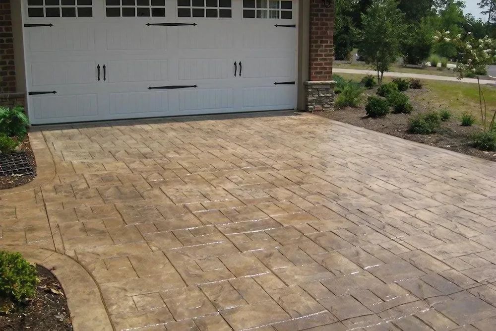 A Brick Driveway Leading to A White Garage Door — Concrete Colour Solutions in Morisset, NSW